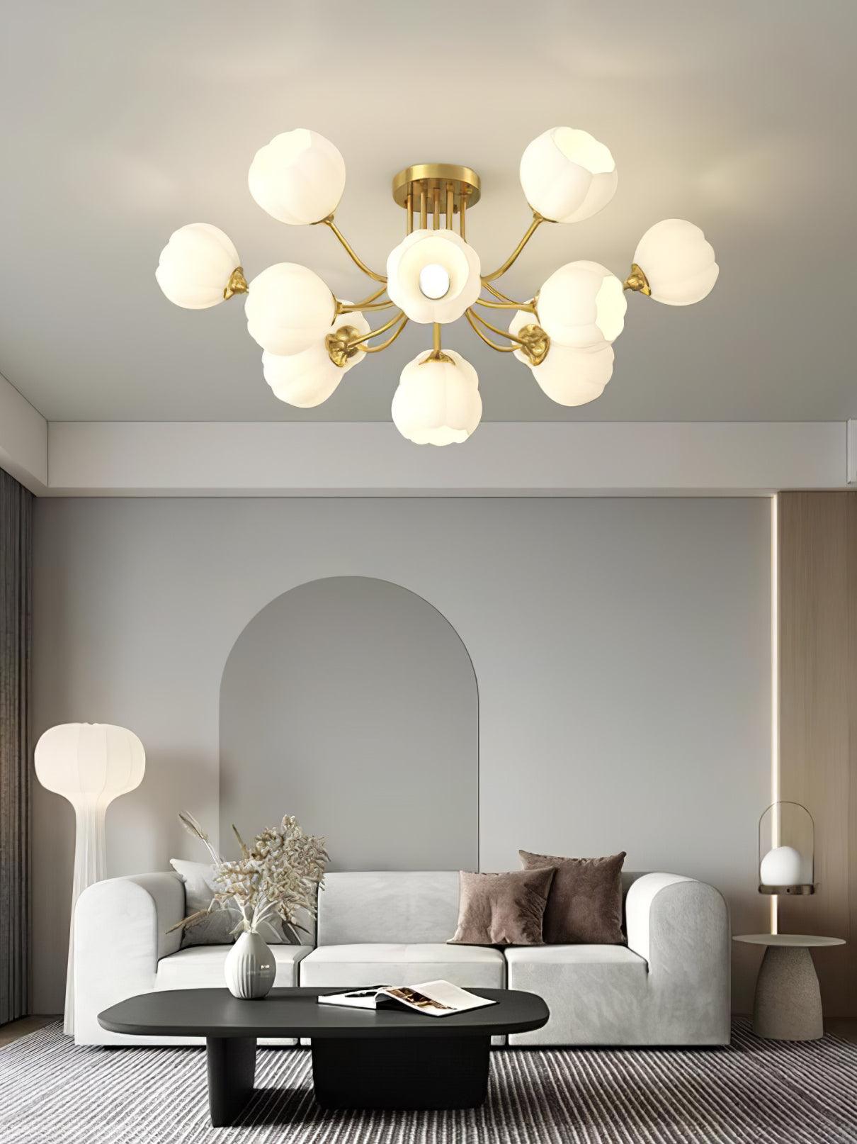 Brass-colour Pumpkin ceiling light with white glass shades above a curved white sofa and black oval table
