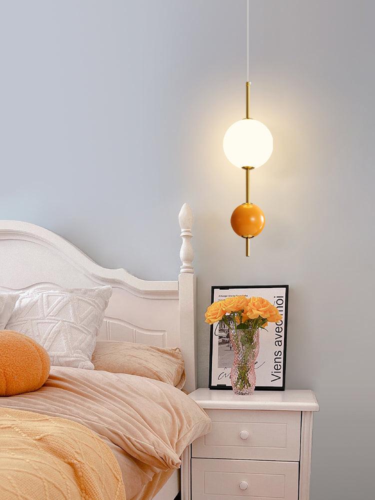 Orange two-ball pendant beside a bed