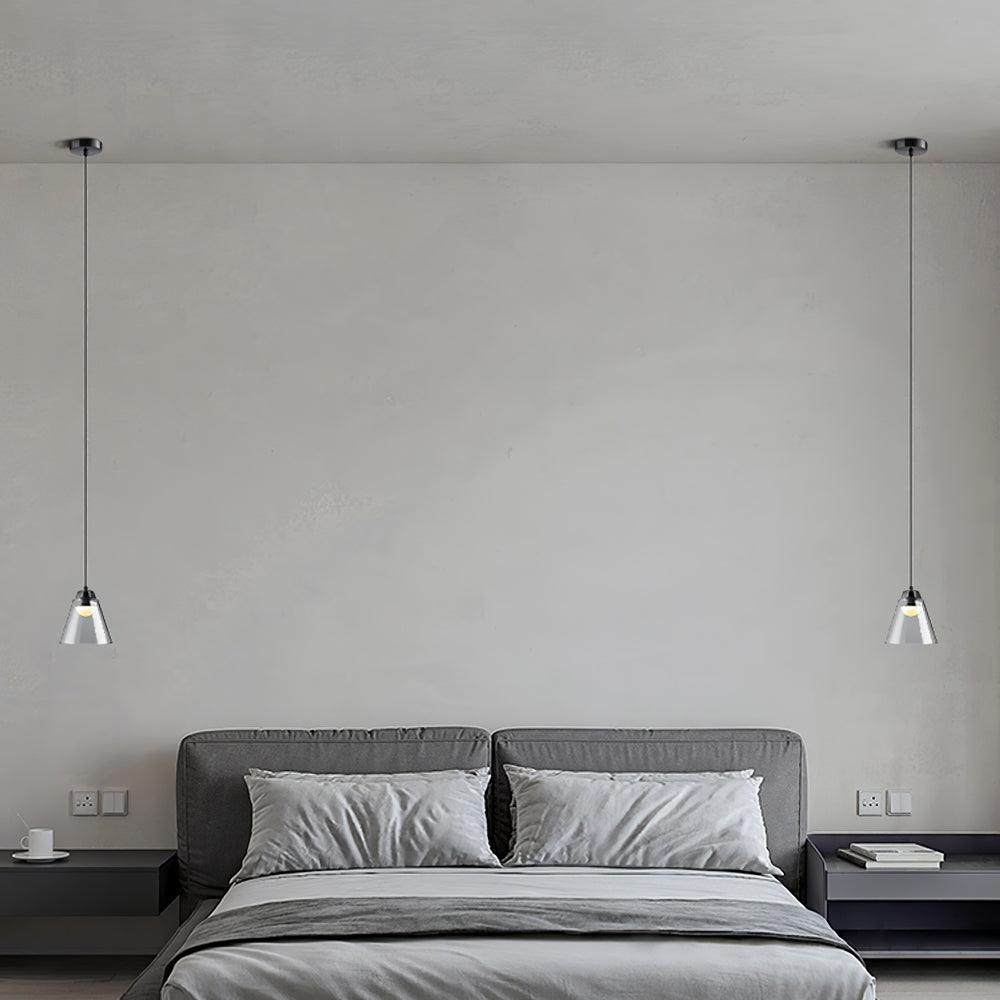 Two separate single pendants beside a bed