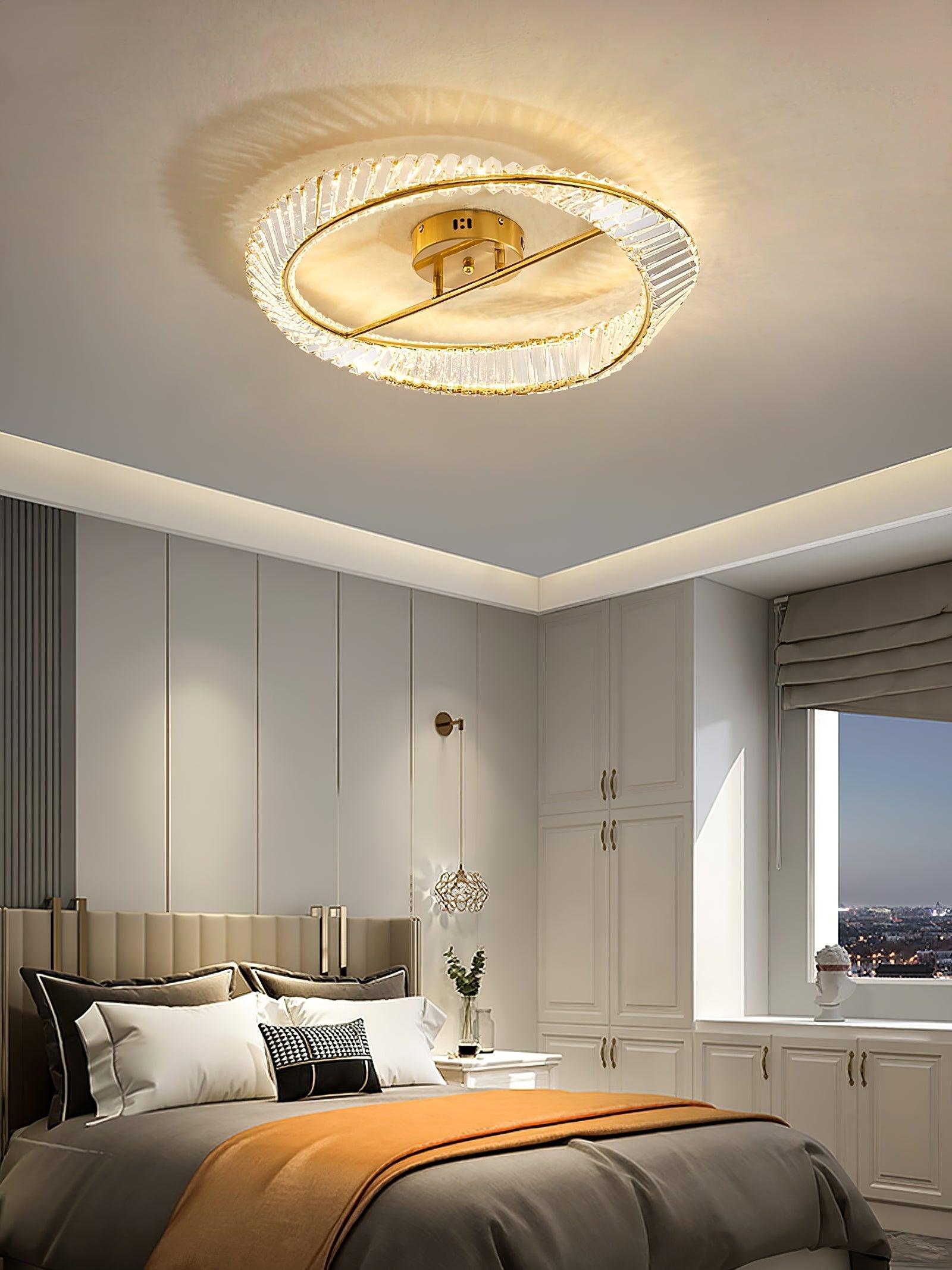 Glass ring ceiling light above a bed with an orange throw and white wardrobe