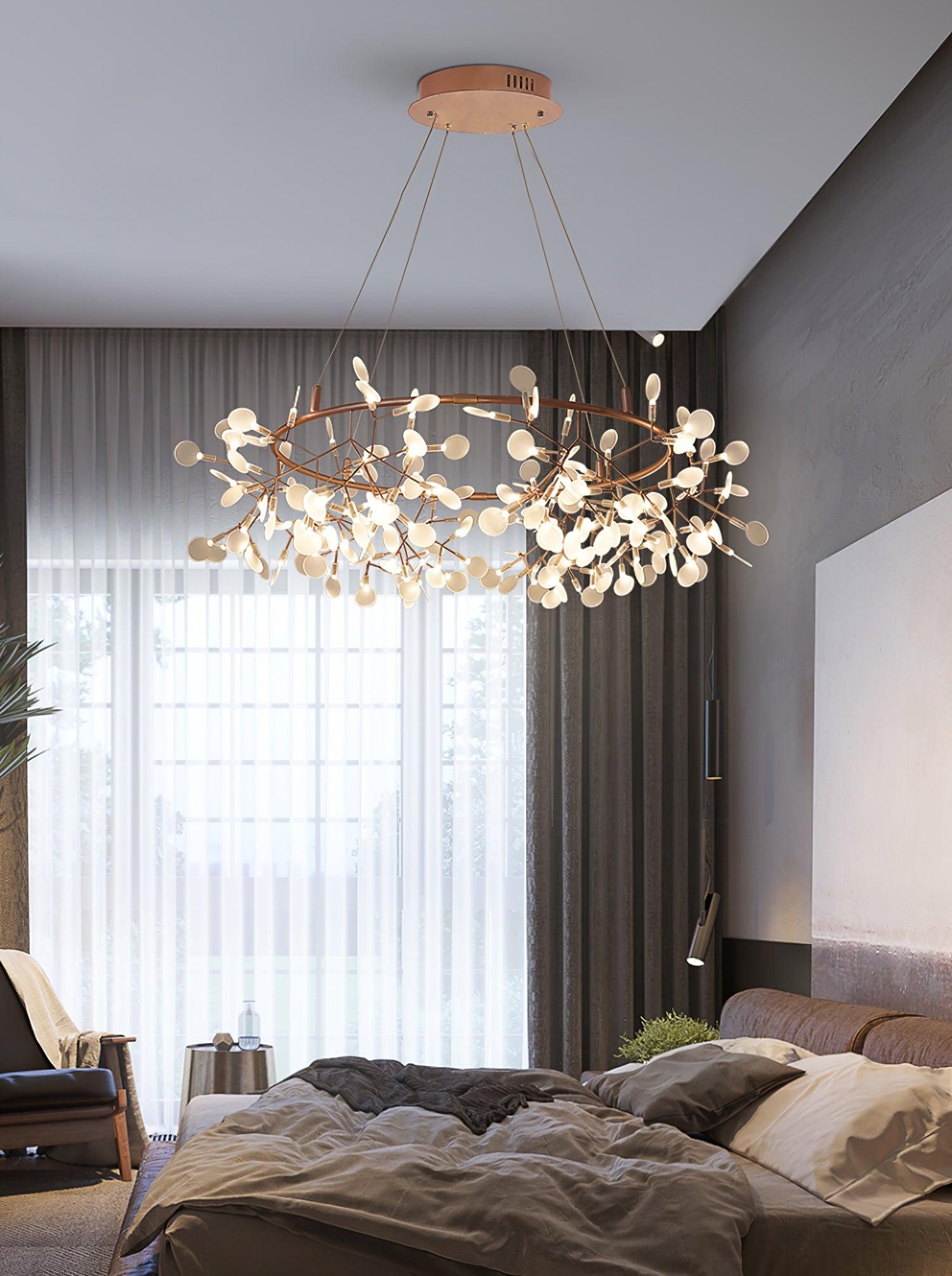 Rose-copper leaf ring chandelier above a grey bed beside a tall sheer-curtained window