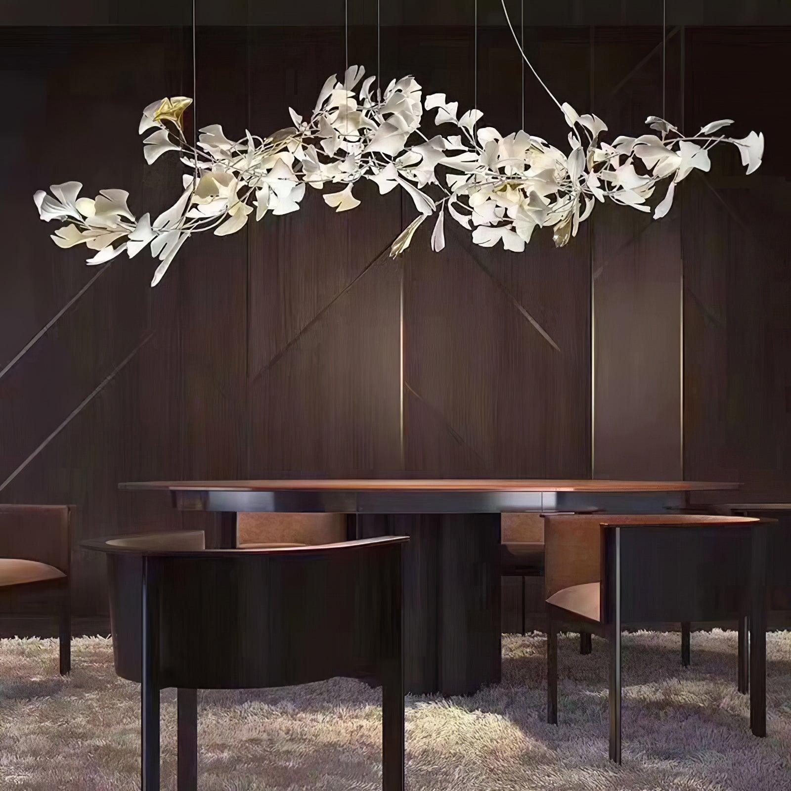 Gold-and-white branching ginkgo chandelier above a dark timber dining table against a timber-panel wall
