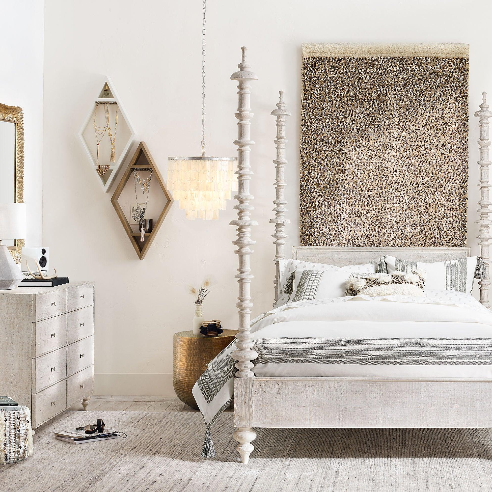 Lit shell pendant beside a white four-poster bed with striped bedding, patterned artwork and jewellery display shelves
