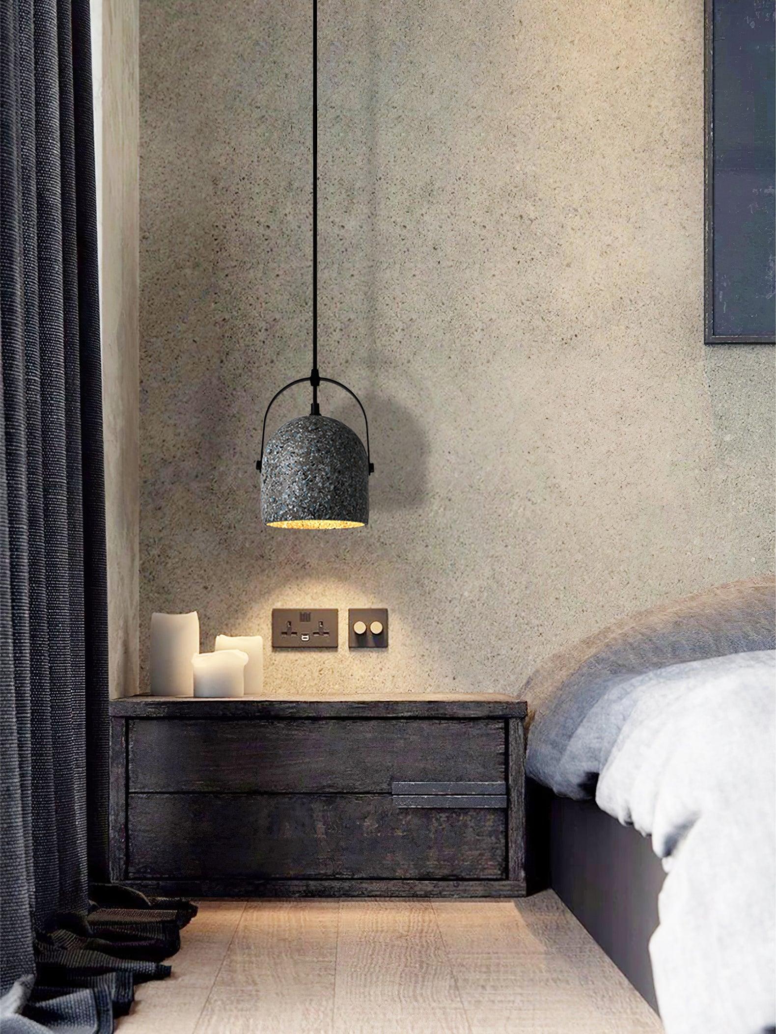 Grey handle-topped cement pendant over bedside furniture