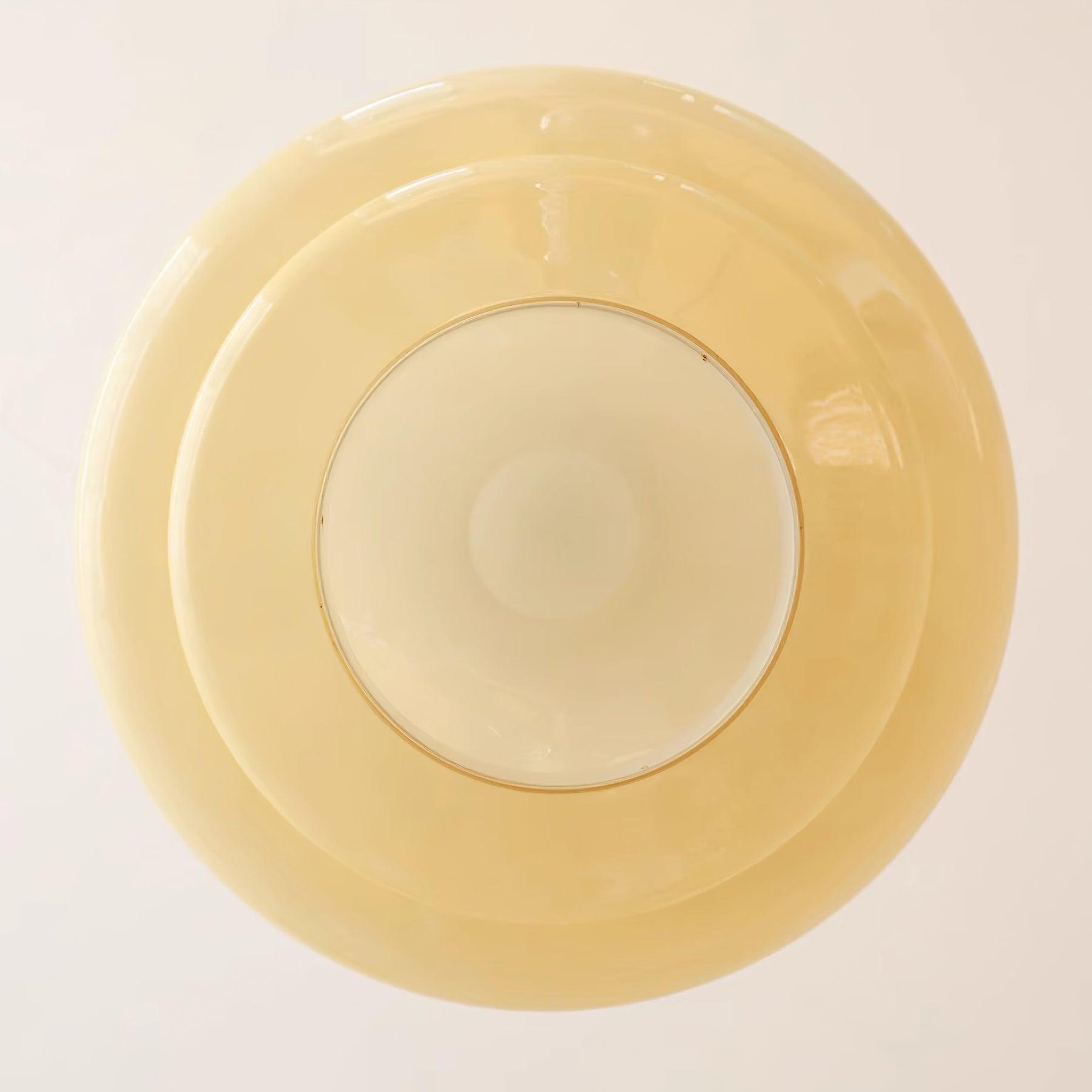 Direct underside detail of a pale circular face within concentric yellow glass edges and a thin rim