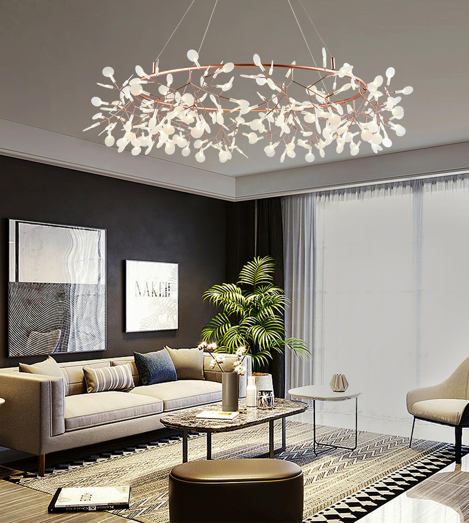 Rose-copper leaf ring chandelier over a pale sofa, oval coffee table and dark round ottoman near framed art