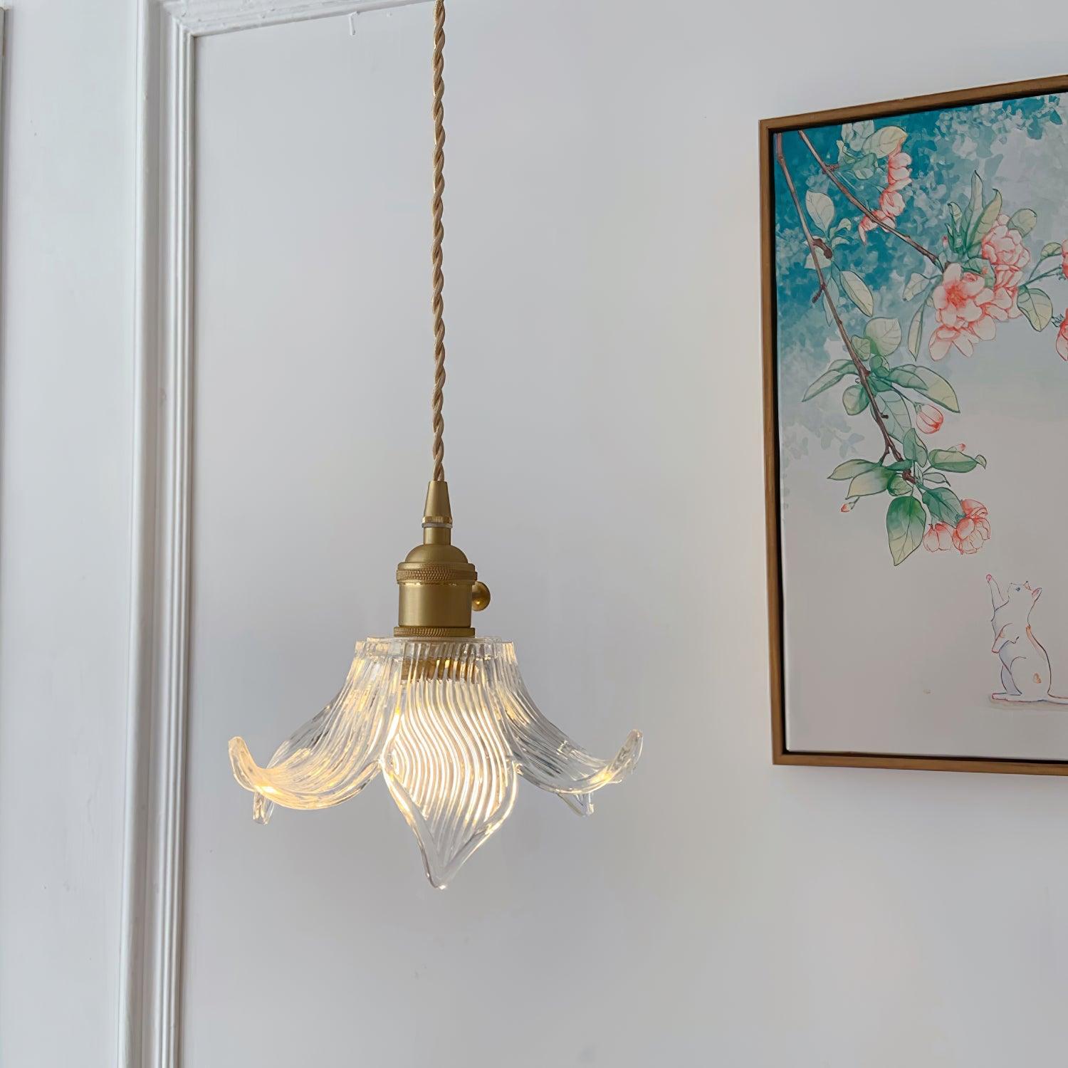 Single lit clear flower shade before white wall panelling and framed floral artwork featuring a white cat.
