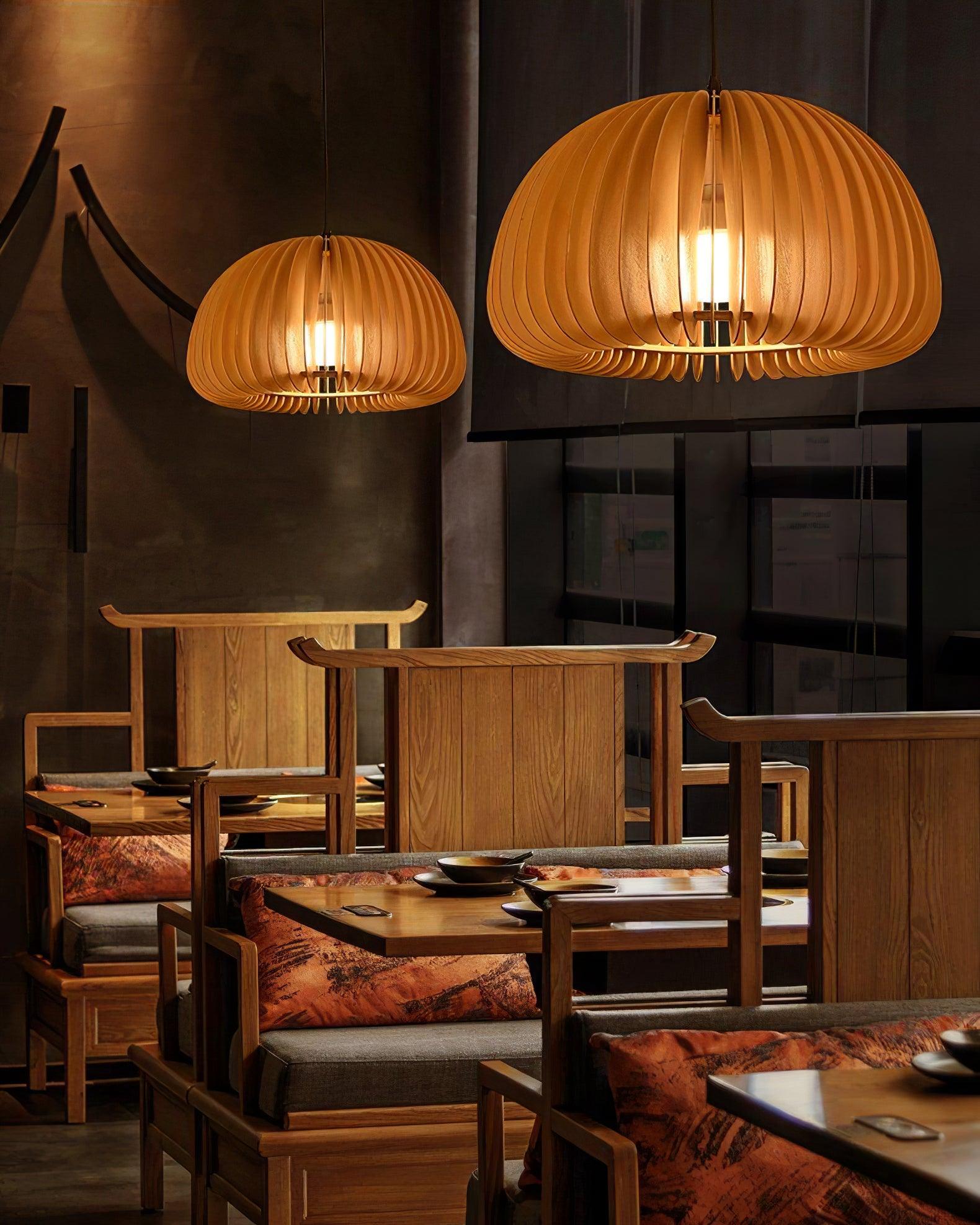 Two glowing wood slat dome pendants above wooden dining tables and chairs in a dark interior
