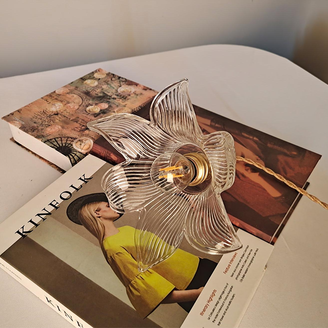 Underside clear ribbed flower shade surrounding a round filament-style bulb on a Kinfolk magazine and patterned books.