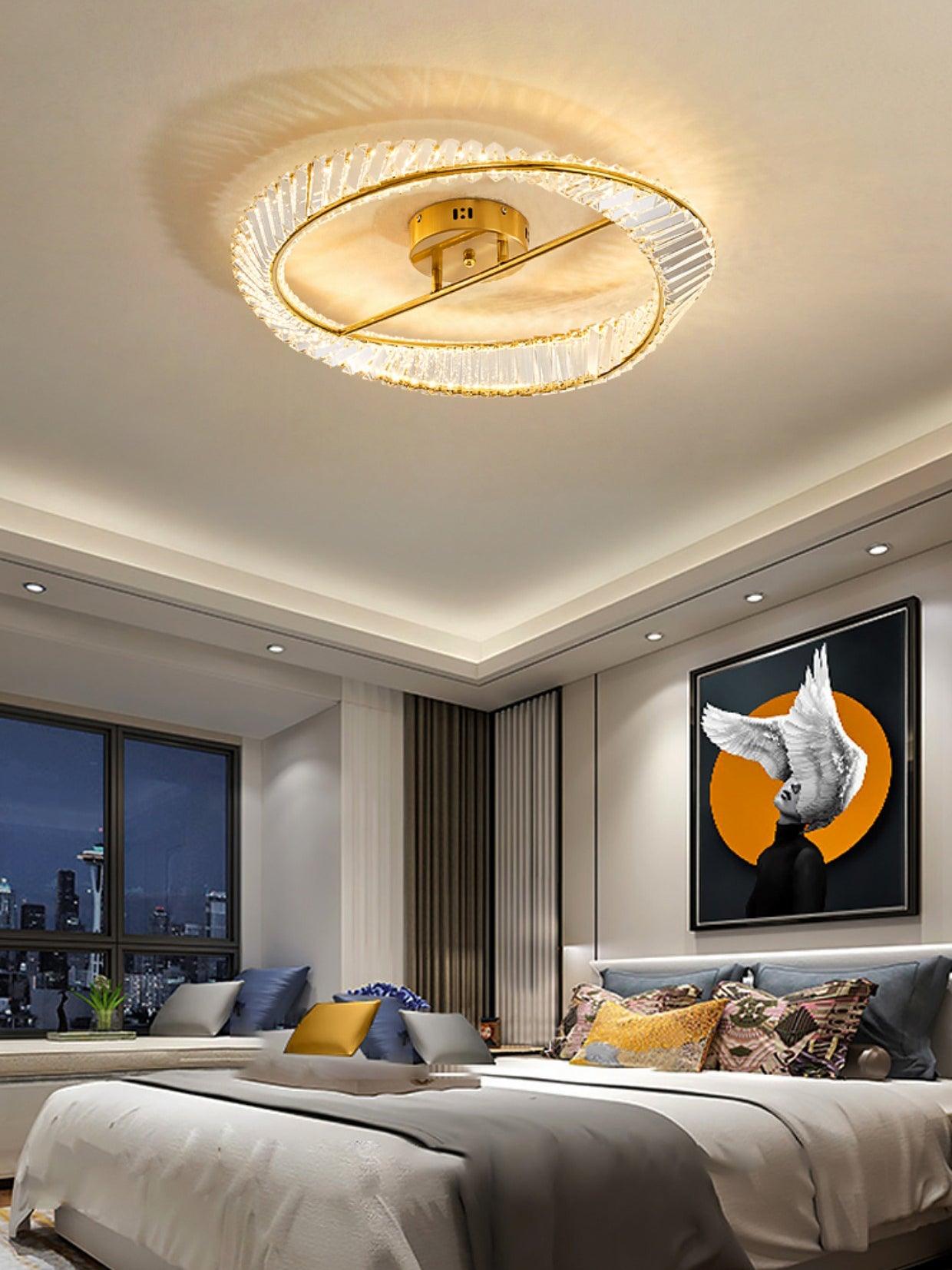 Gold-tone glass ring light above a bed beneath a portrait with a white bird and orange background