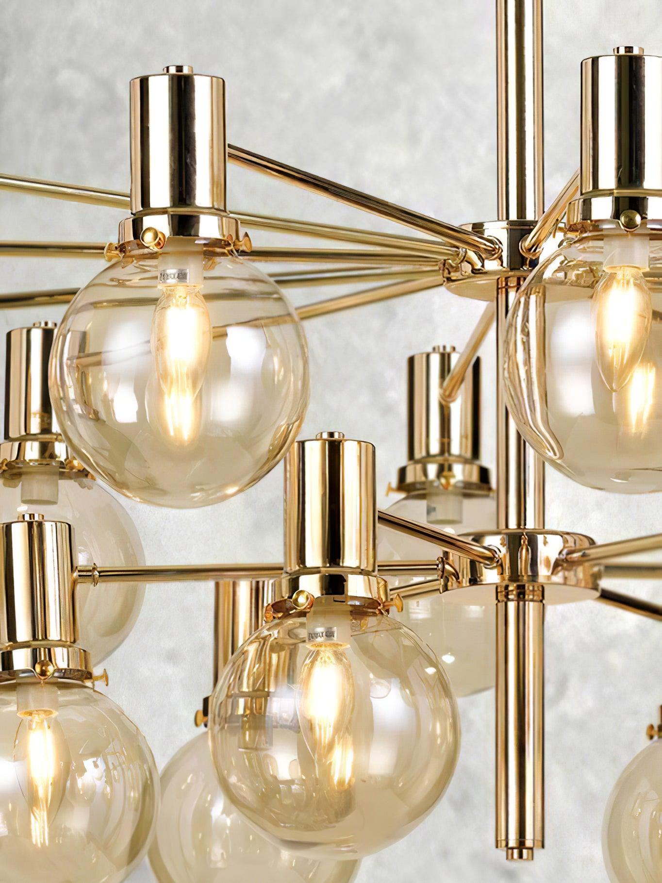 Close view of clear globes with lit filament-style bulbs, gold-tone holders with side screws and two radial hubs.