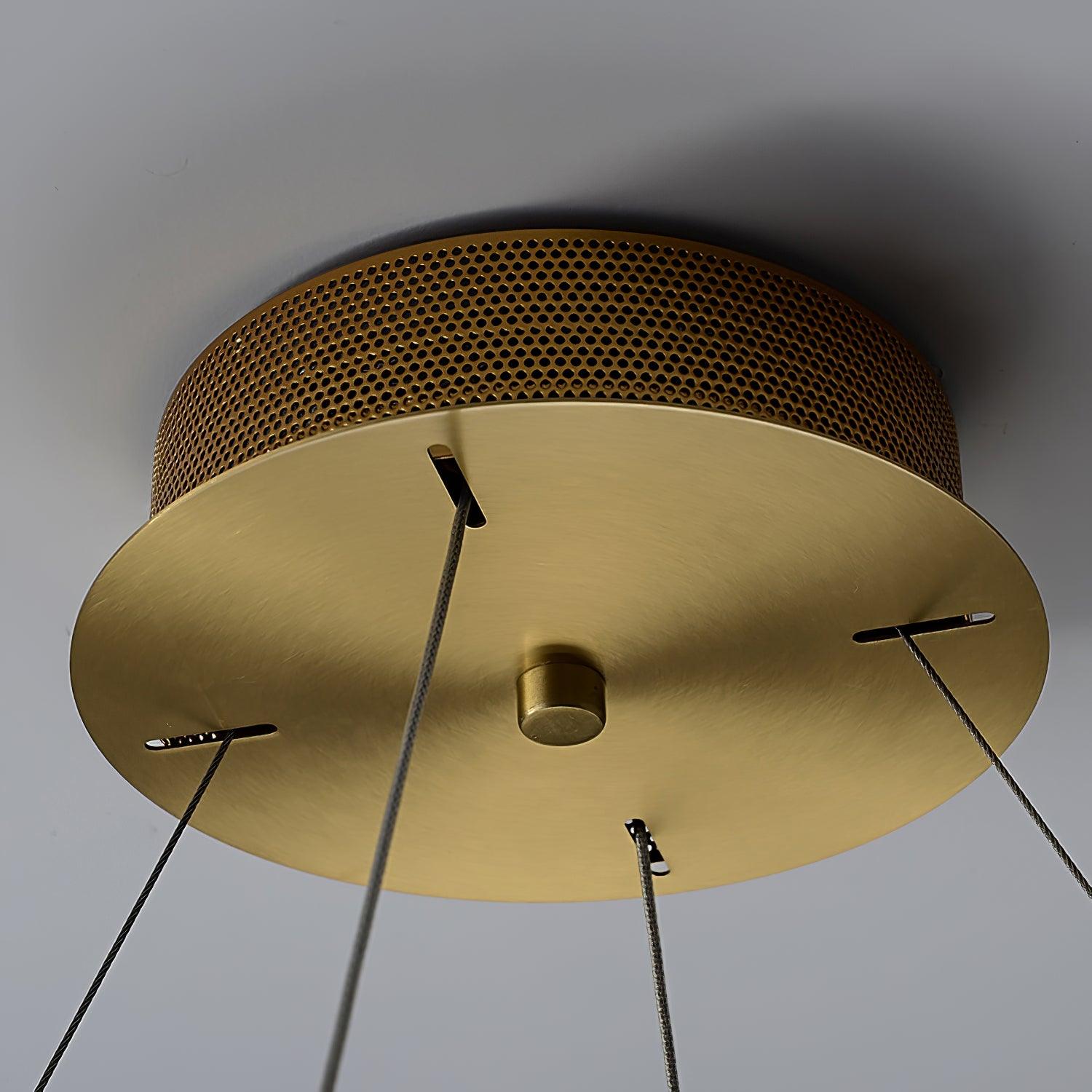 Close-up of warm-metal round canopy with perforated side, four cable slots, suspension lines and central cap