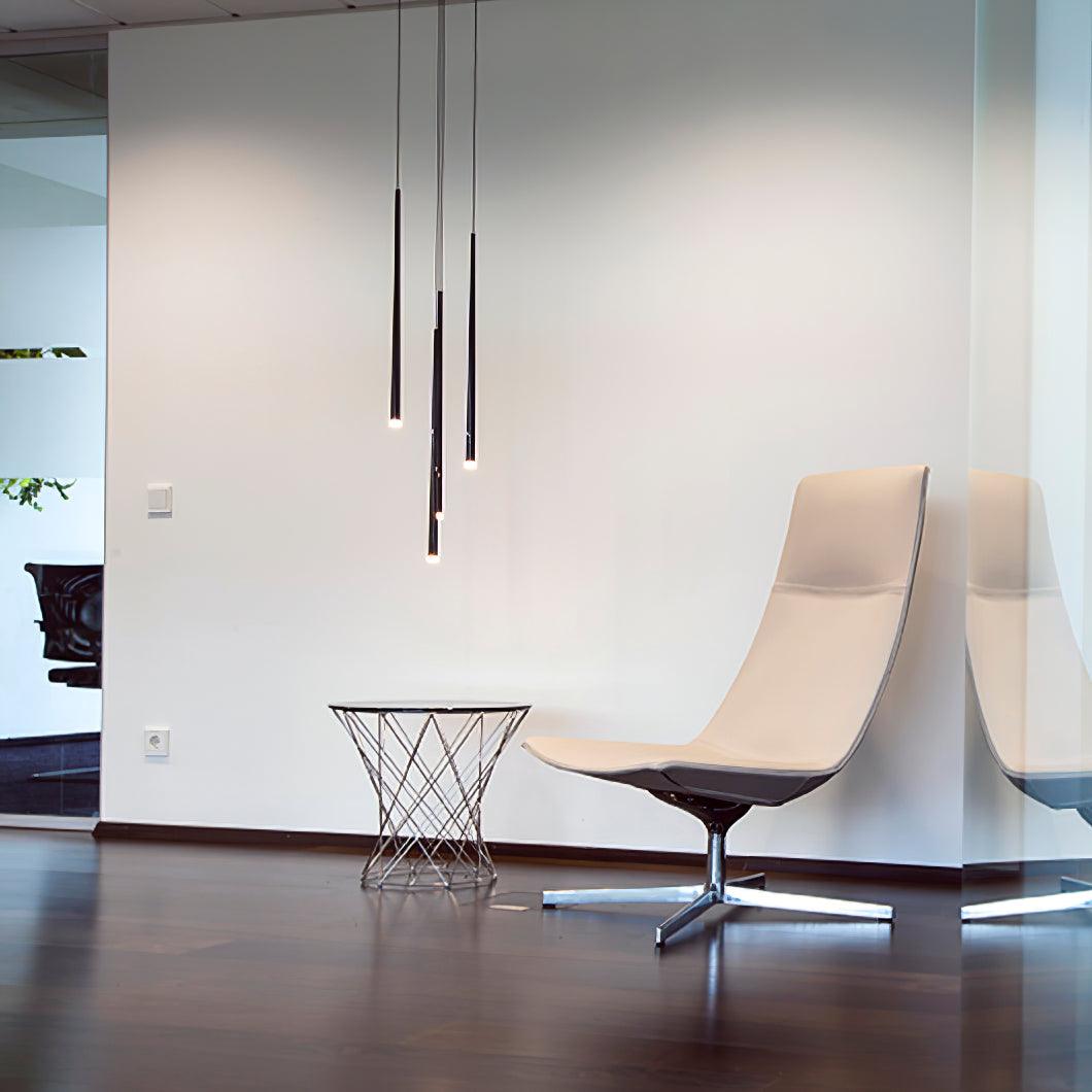 Black pendant tubes with glowing ends beside a cream swivel chair and wire-frame table