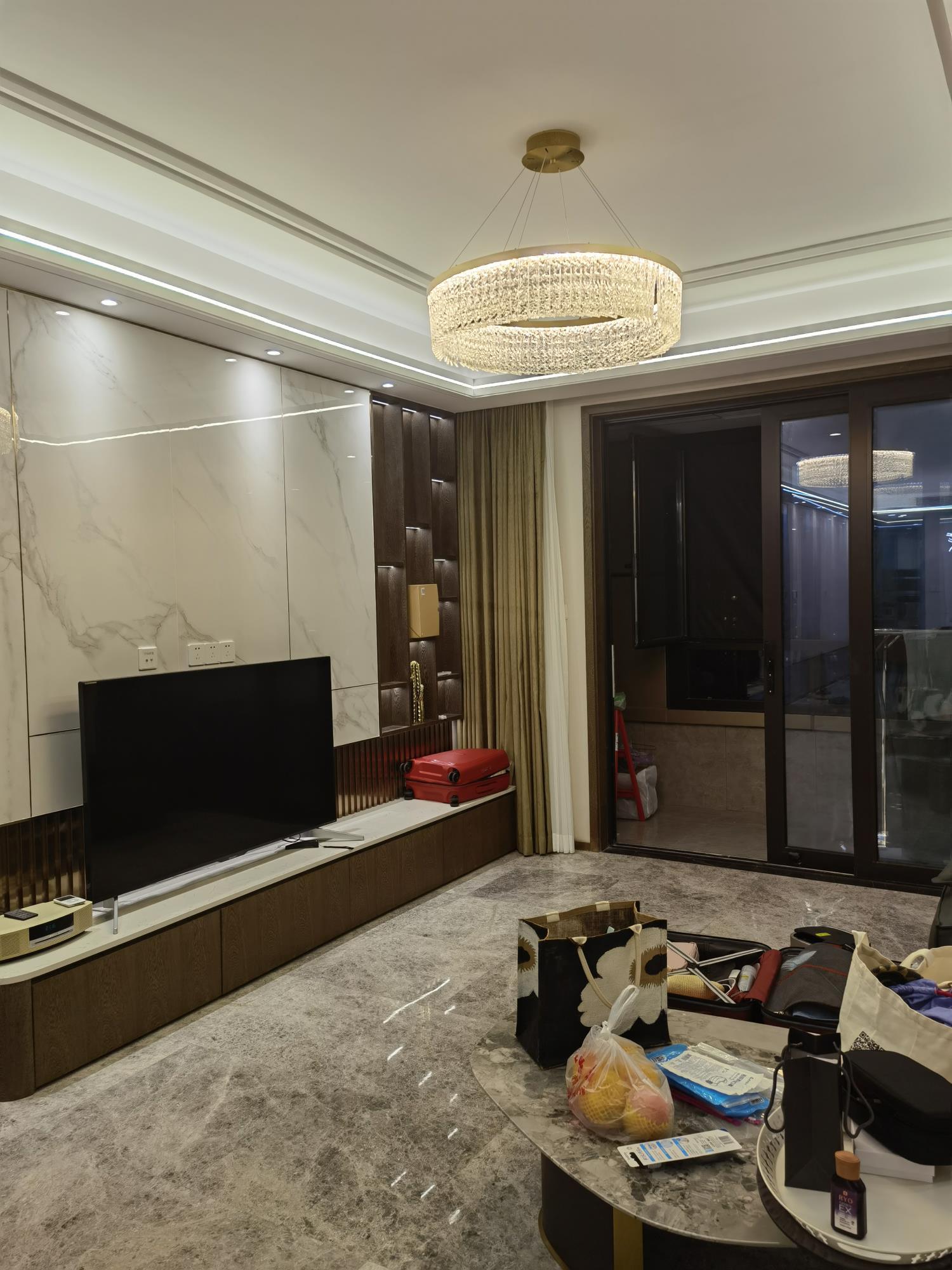 Installed ring chandelier in living room with television wall, balcony glazing, curtains, coffee table and household objects