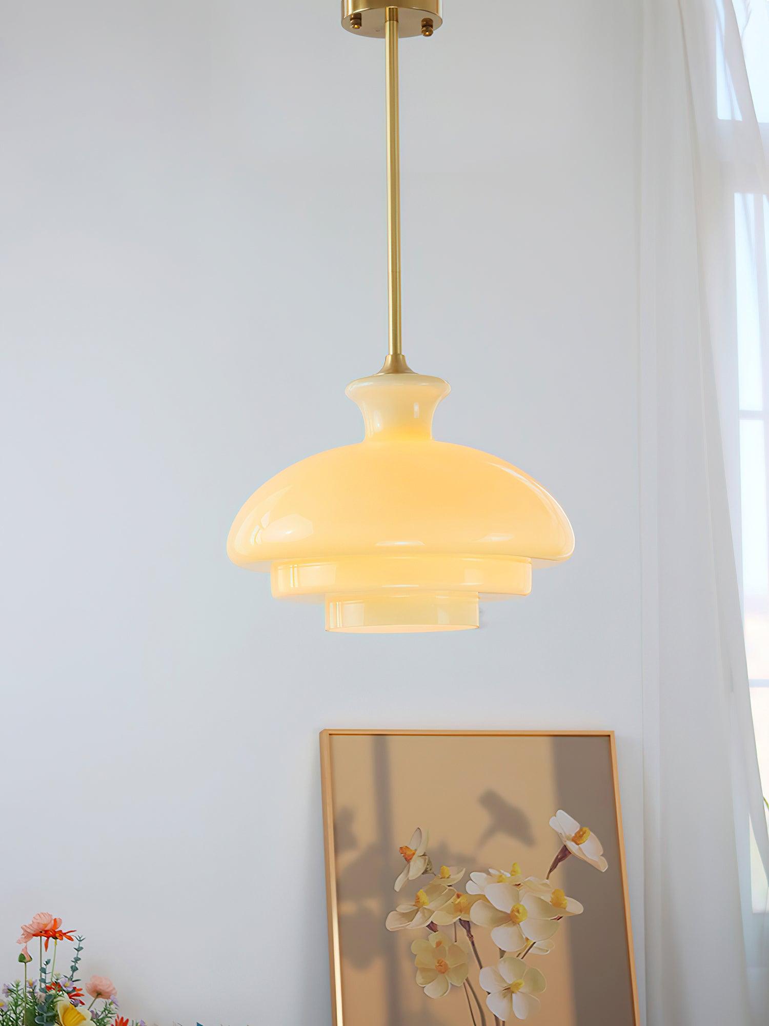 Glowing yellow stepped dome on a gold-tone rod near white curtains, framed art and orchids