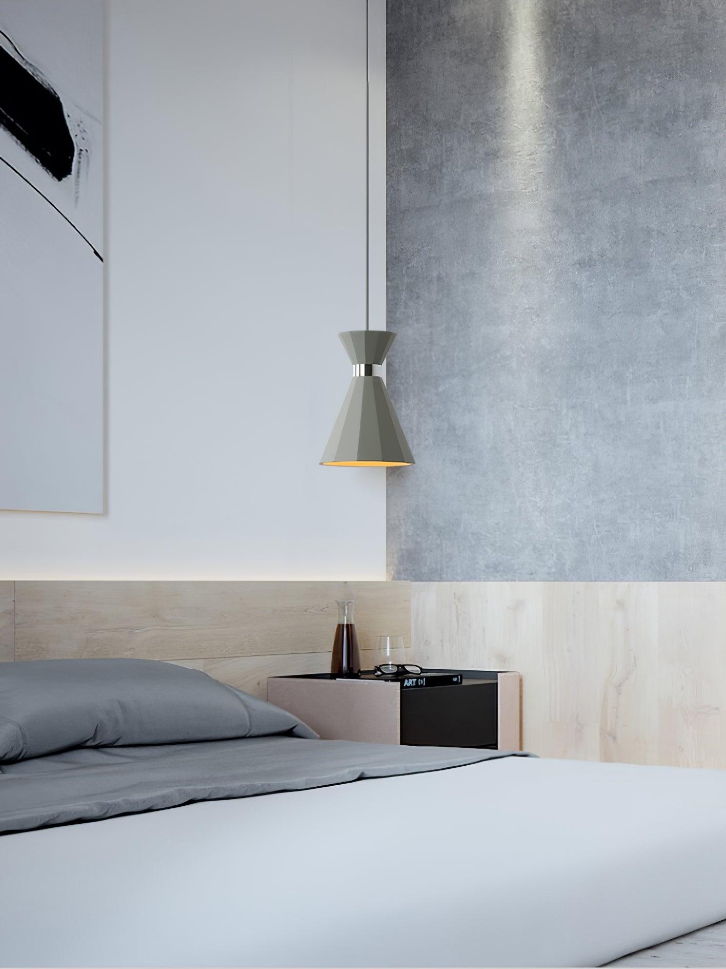 Tall grey pendant suspended beside a bed