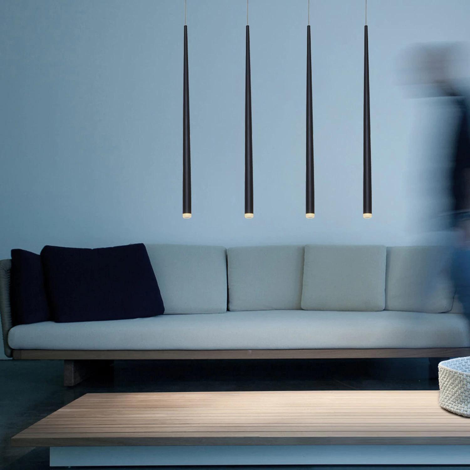 Four black tube pendants aligned in front of a pale blue sofa and low wooden table