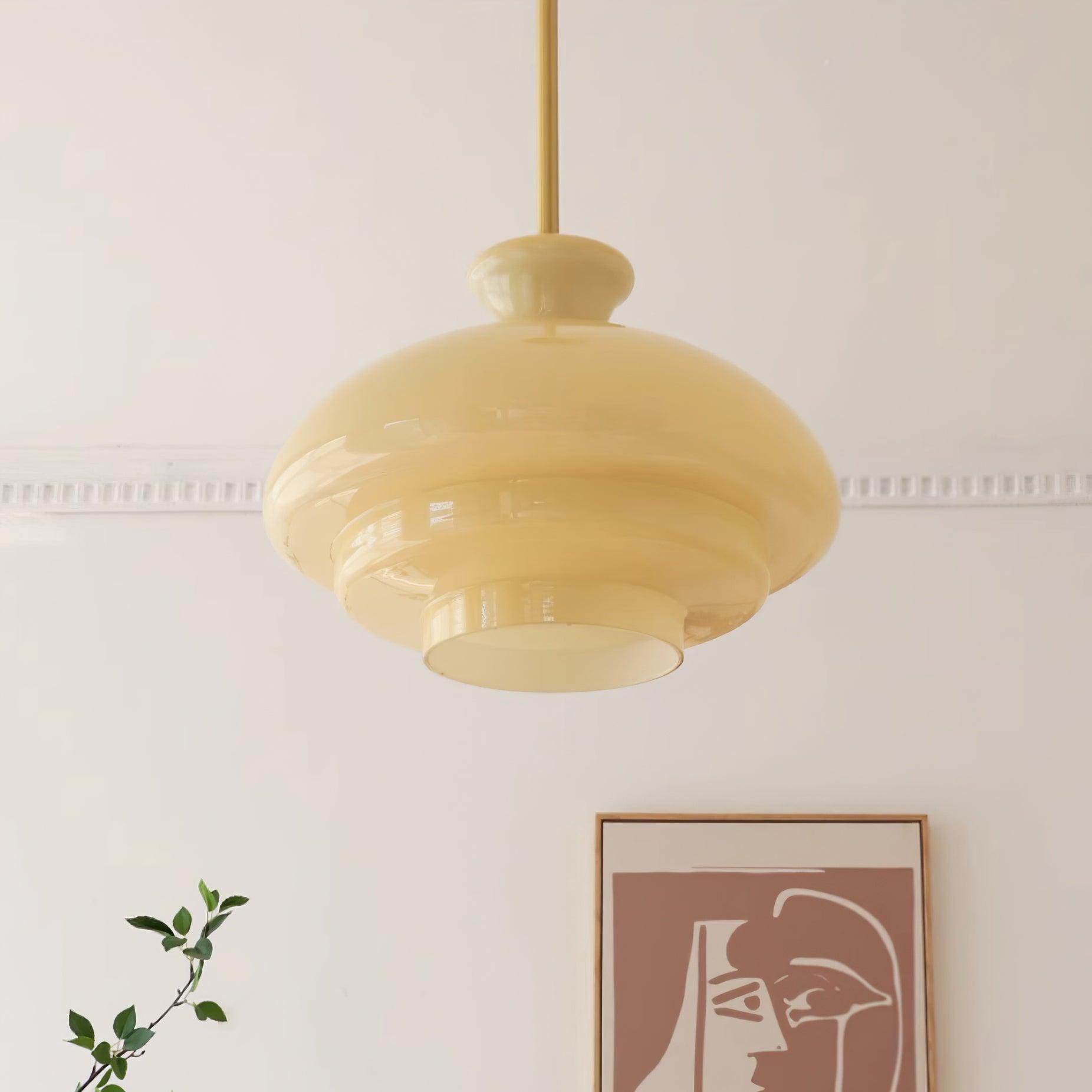 Pale-yellow stepped dome and gold-tone rod before framed two-face artwork and greenery