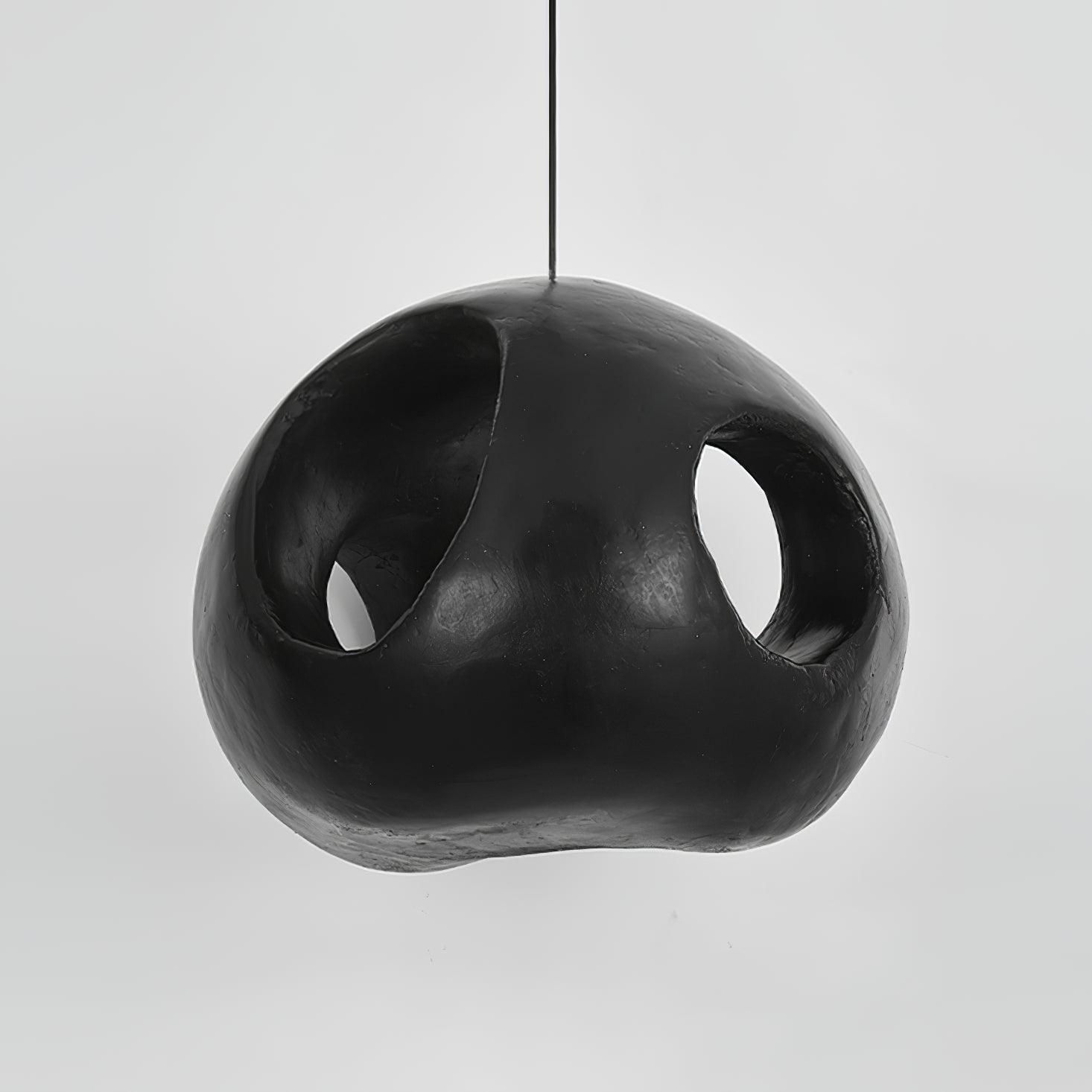 Unlit black rounded pendant with oval openings and a dark interior, suspended from a thin cord against grey