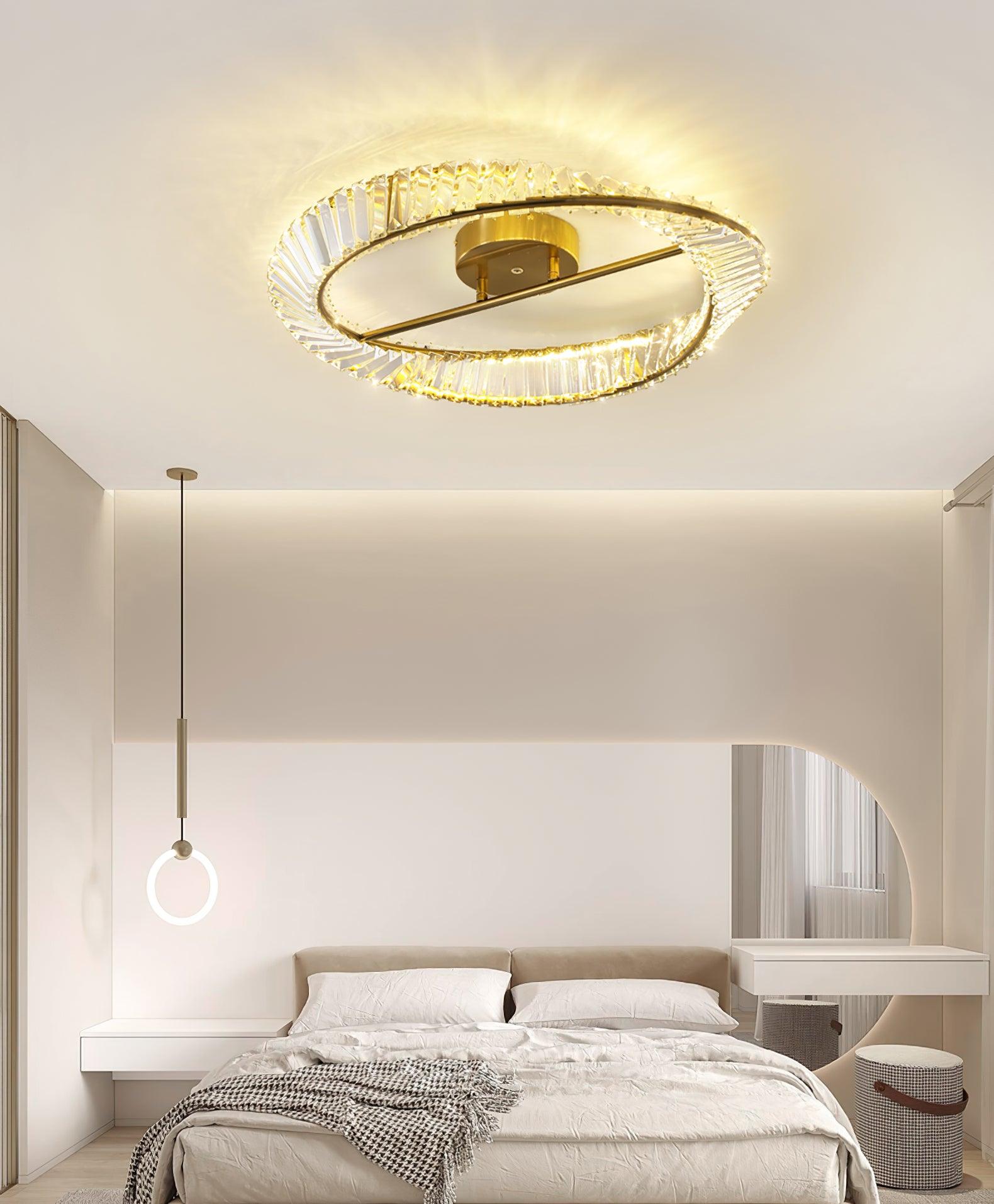 Glass ring ceiling light above a beige bed with a separate hanging ring pendant beside it