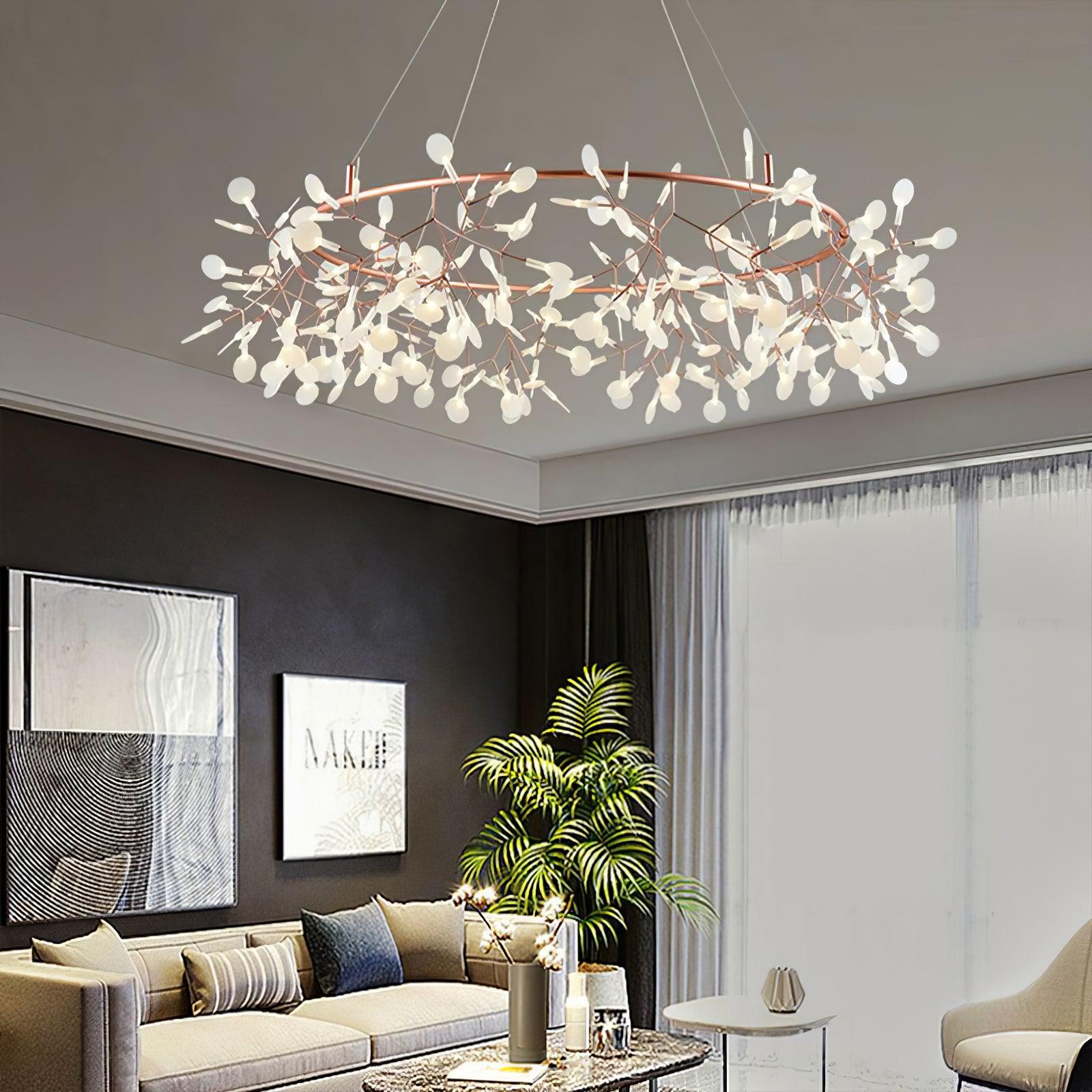 Wide rose-copper leaf ring chandelier above a pale sofa, patterned coffee table and tall palm beside dark artwork