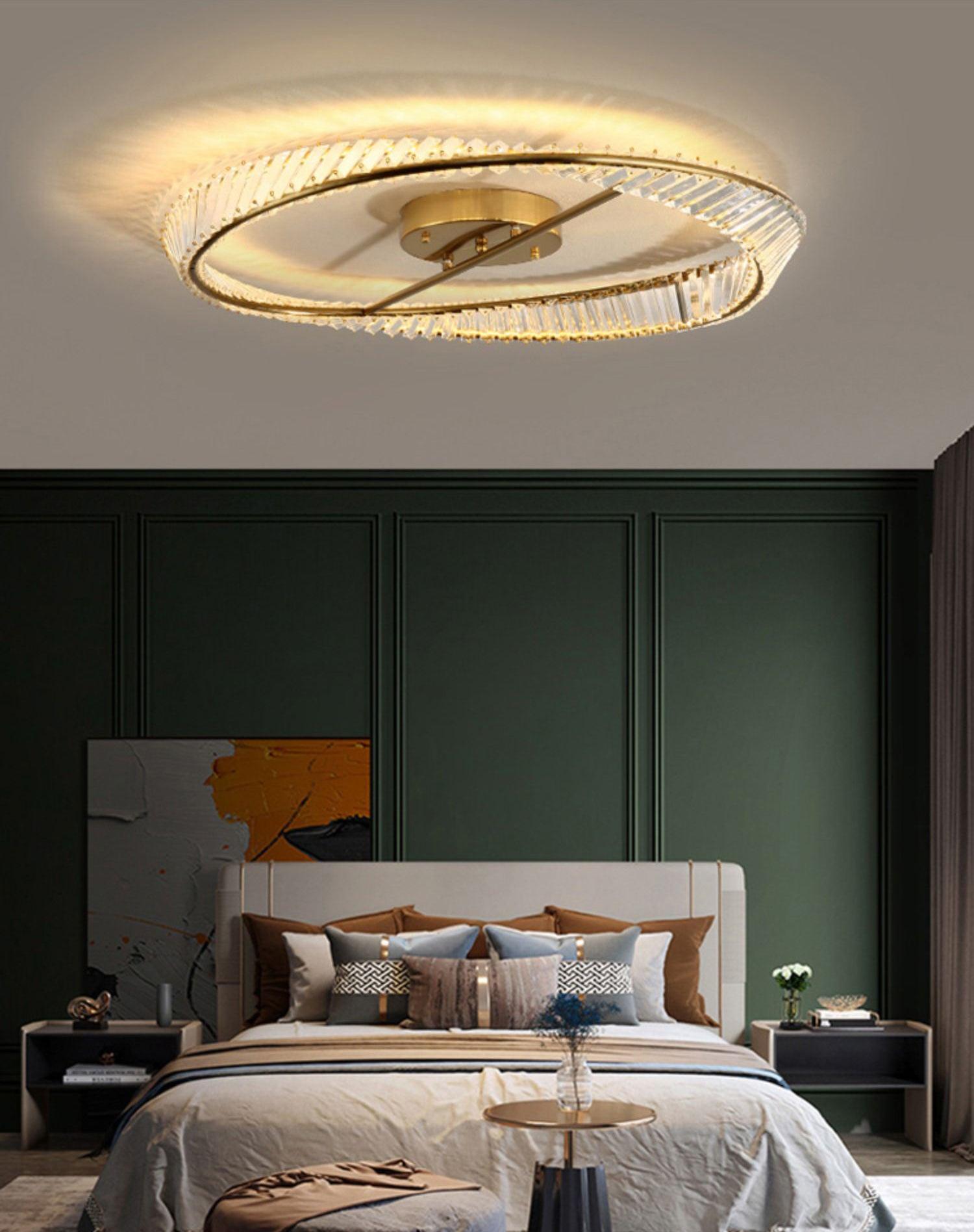 Illuminated ring ceiling light above a bed with a tall pale headboard and dark green wall