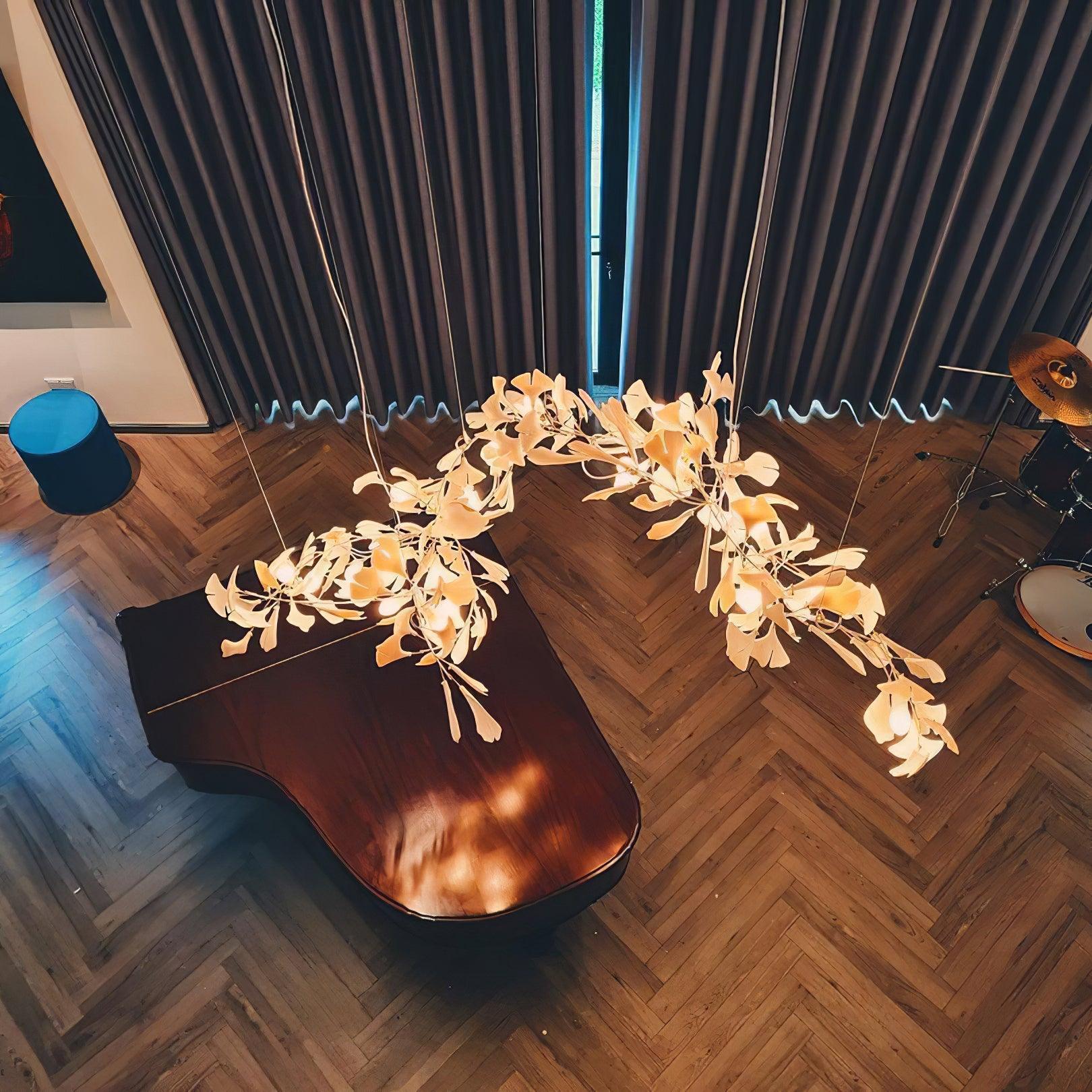White branching leaf chandelier viewed from above a grand piano on a herringbone floor beside a drum kit