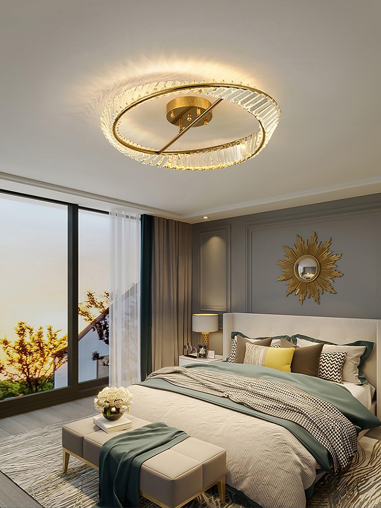 Illuminated ring ceiling light above a bed with a green runner and sunburst wall mirror