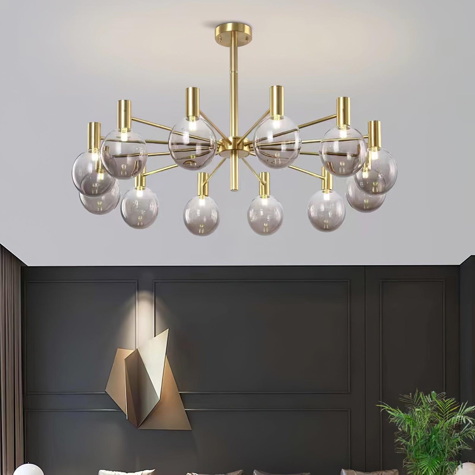 Twelve-clear-globe chandelier above a dark panelled wall with a folded gold-tone geometric sculpture and leafy plant.
