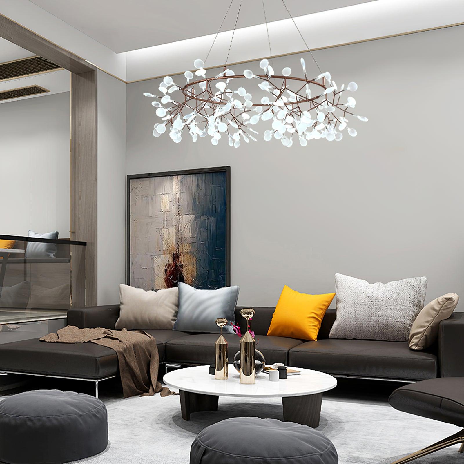 Leaf ring chandelier with bright white tips above a dark sofa, yellow cushion and round white coffee table