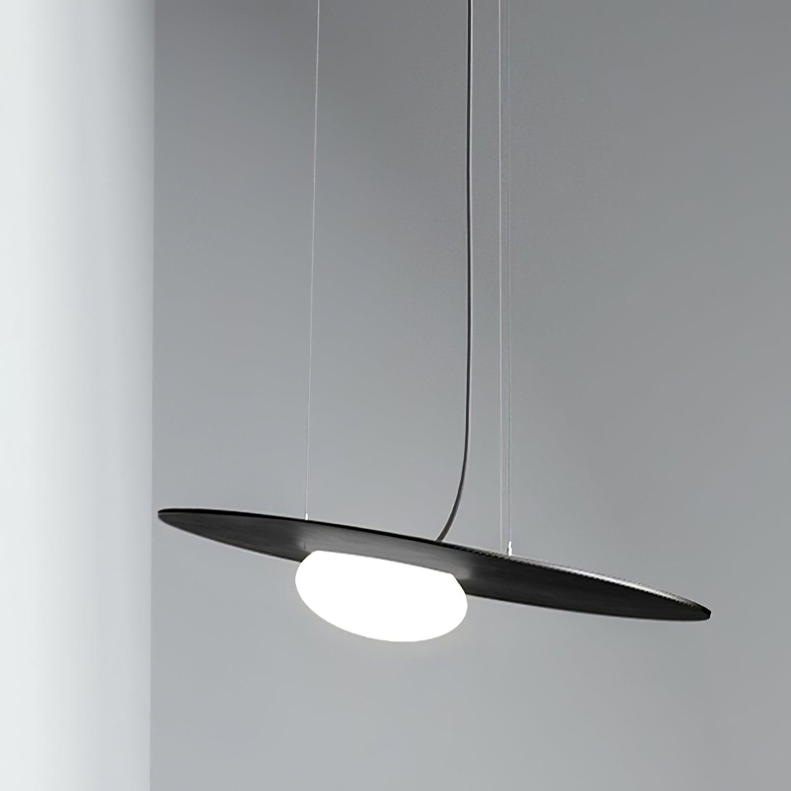 Close low side view of black disc and glowing white diffuser beneath fine support cables and curved dark cord against grey.