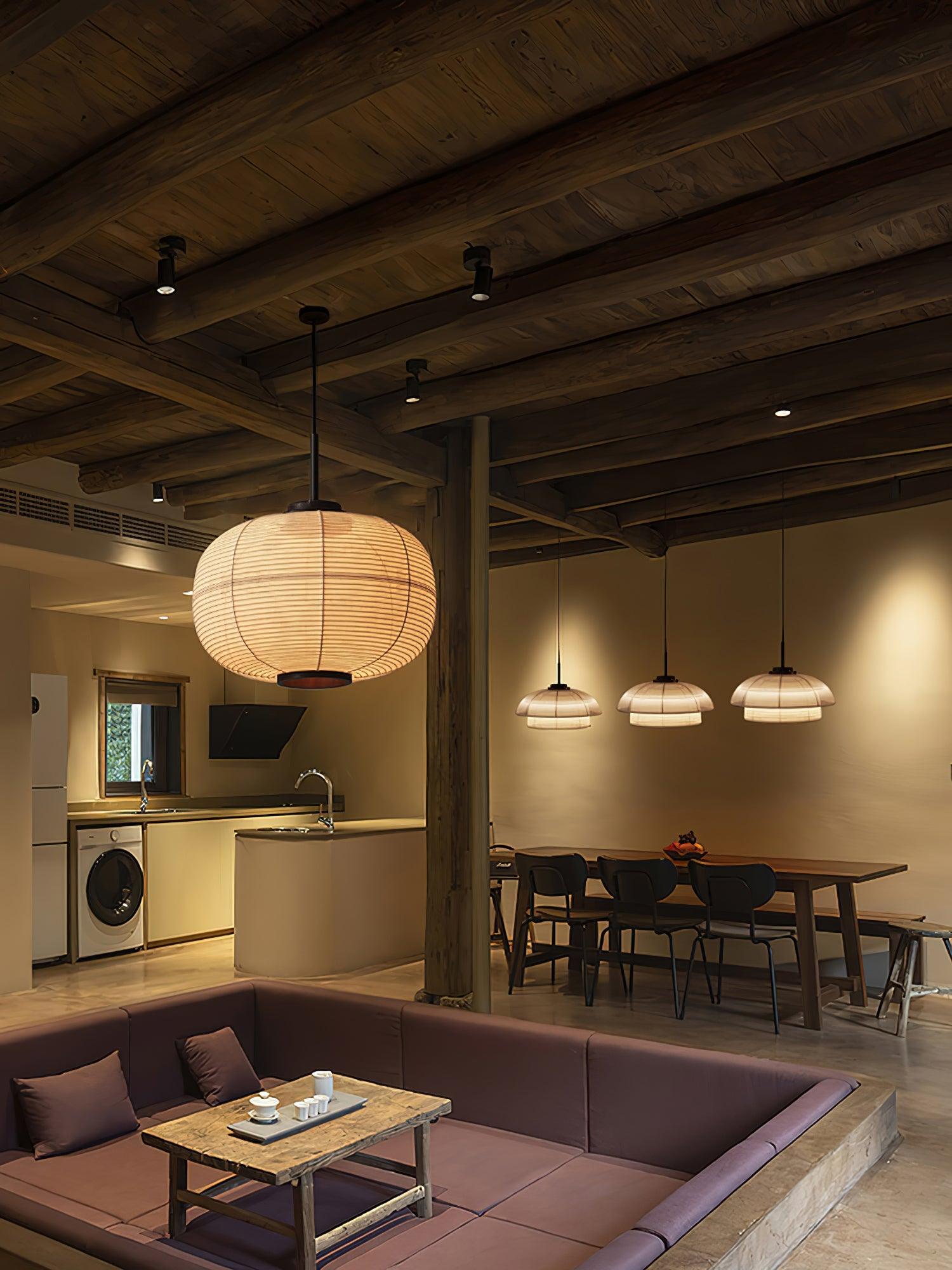 Portrait oval fabric pendant above a seating area, with three smaller dome-and-collar pendants behind over a table