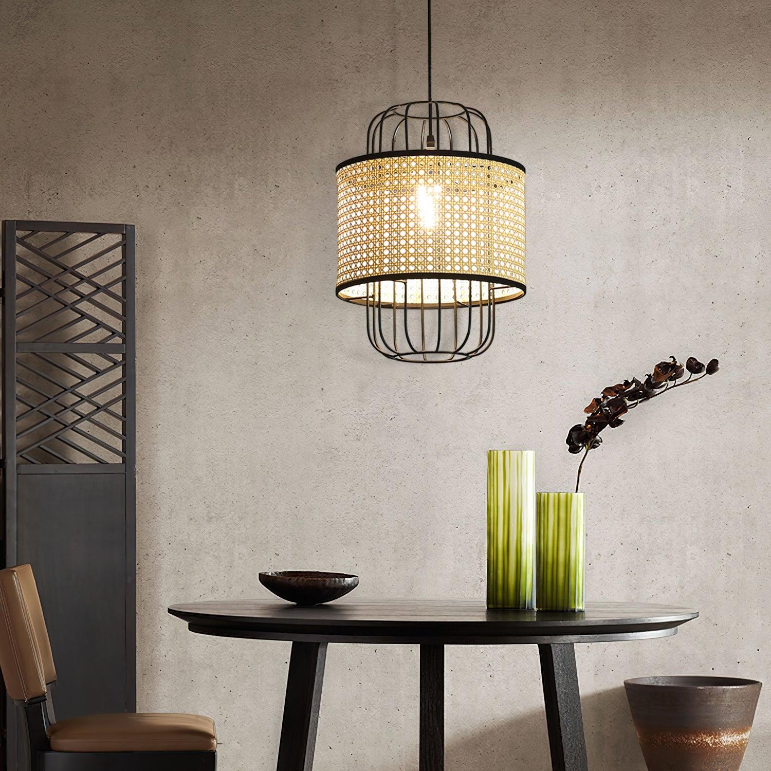 Lit rattan cage pendant above a round dark table with green vases
