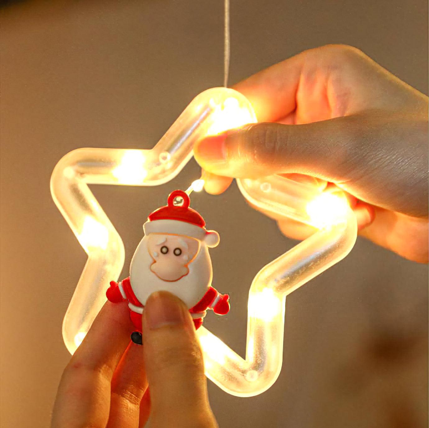 Hand holding a lit star ornament with a Santa figure