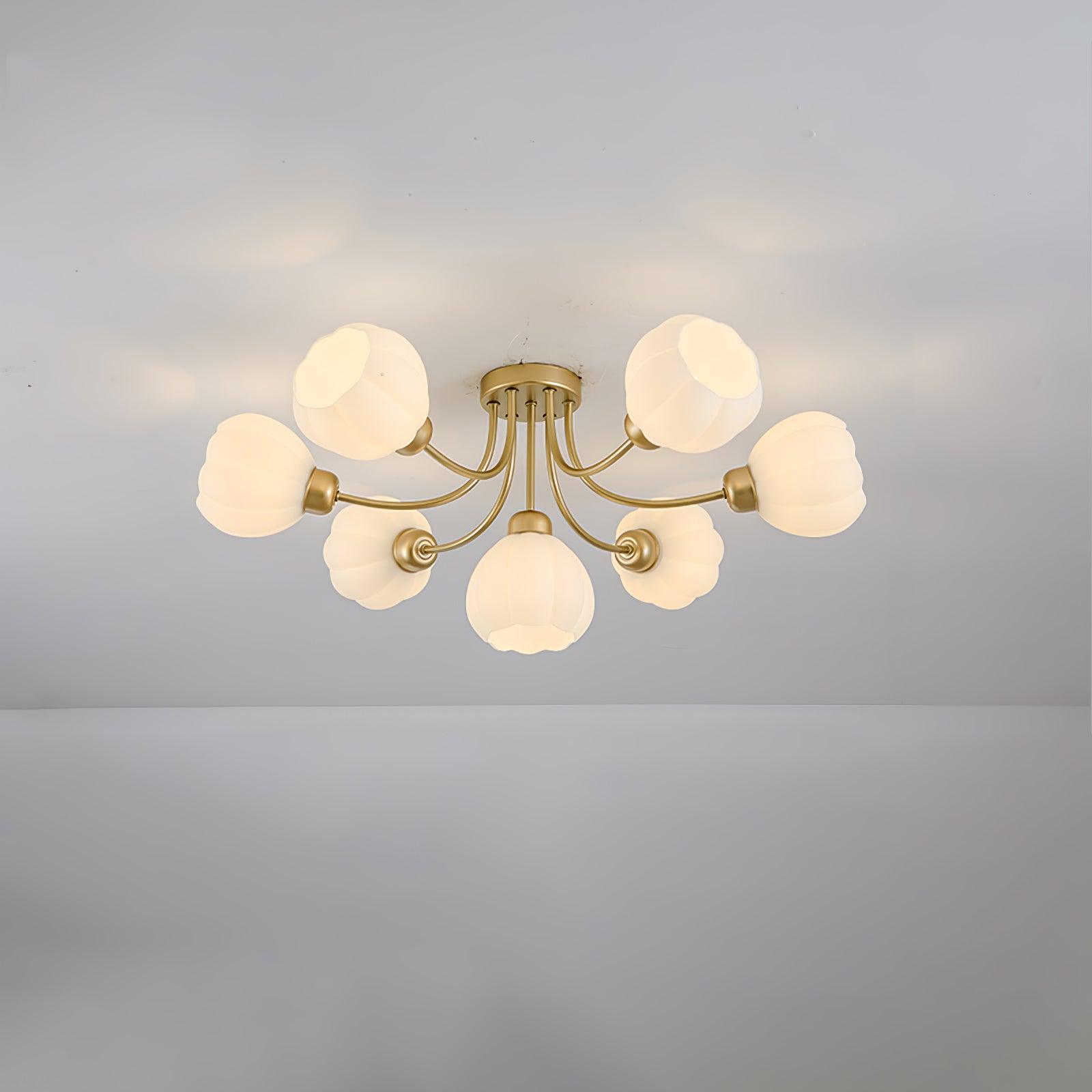 Seven-head Pumpkin ceiling light installed at the ceiling, with brass-colour arms and glowing white glass shades