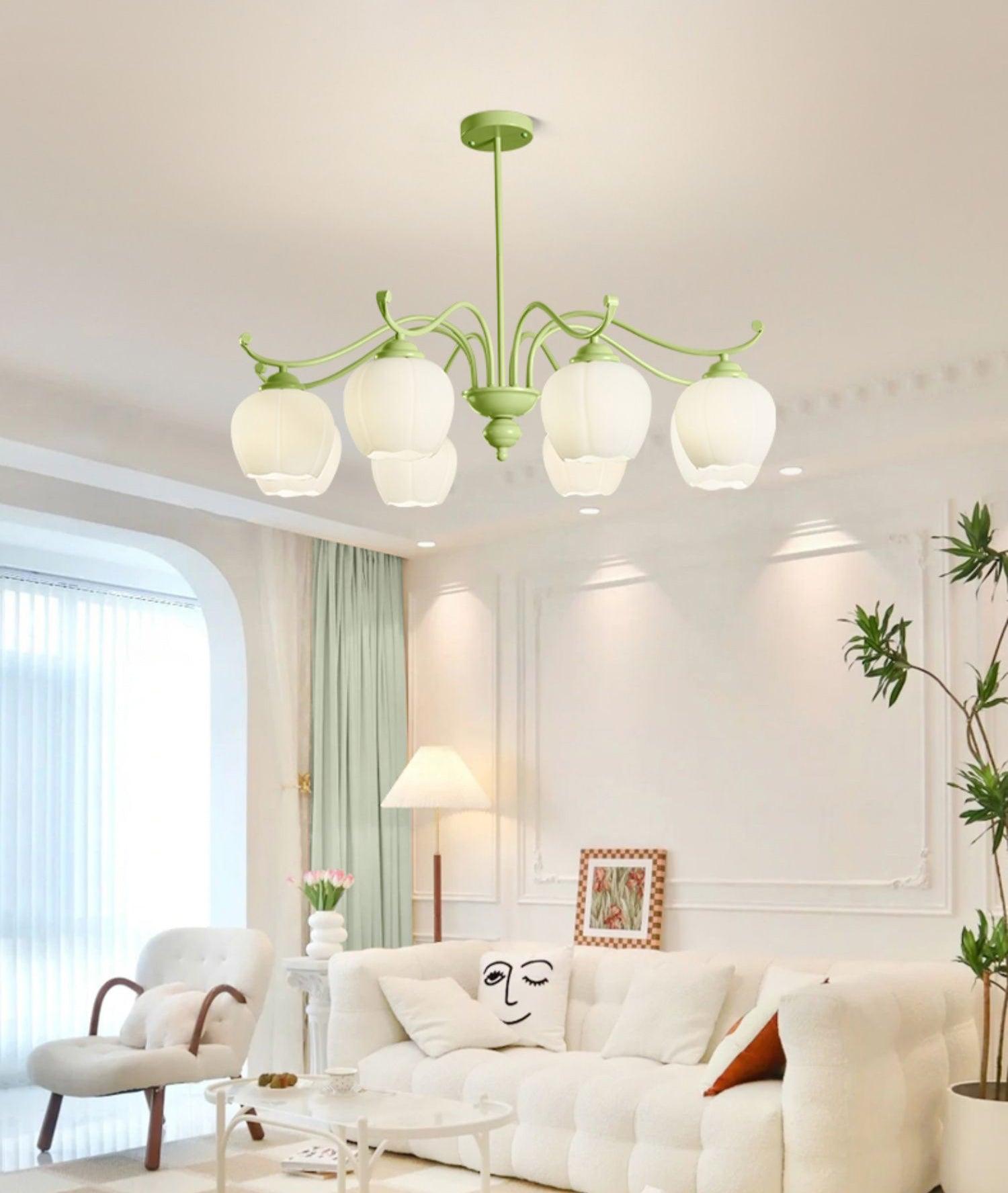 Green eight-light chandelier above a white sofa with a face-pattern cushion beside pale green curtains and a plant