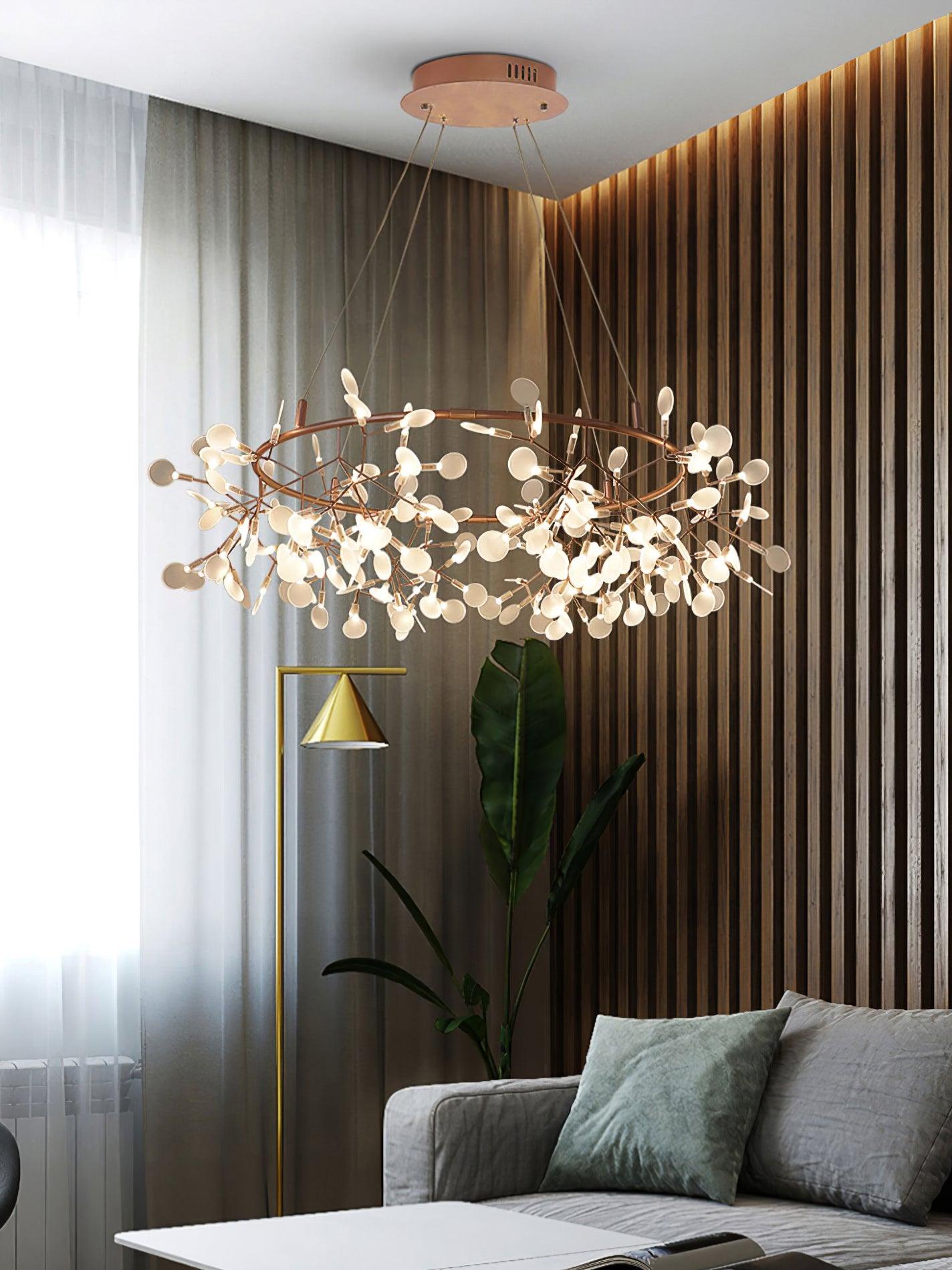 Rose-copper leaf ring chandelier over a grey sofa with green cushion beside timber slats and a plant