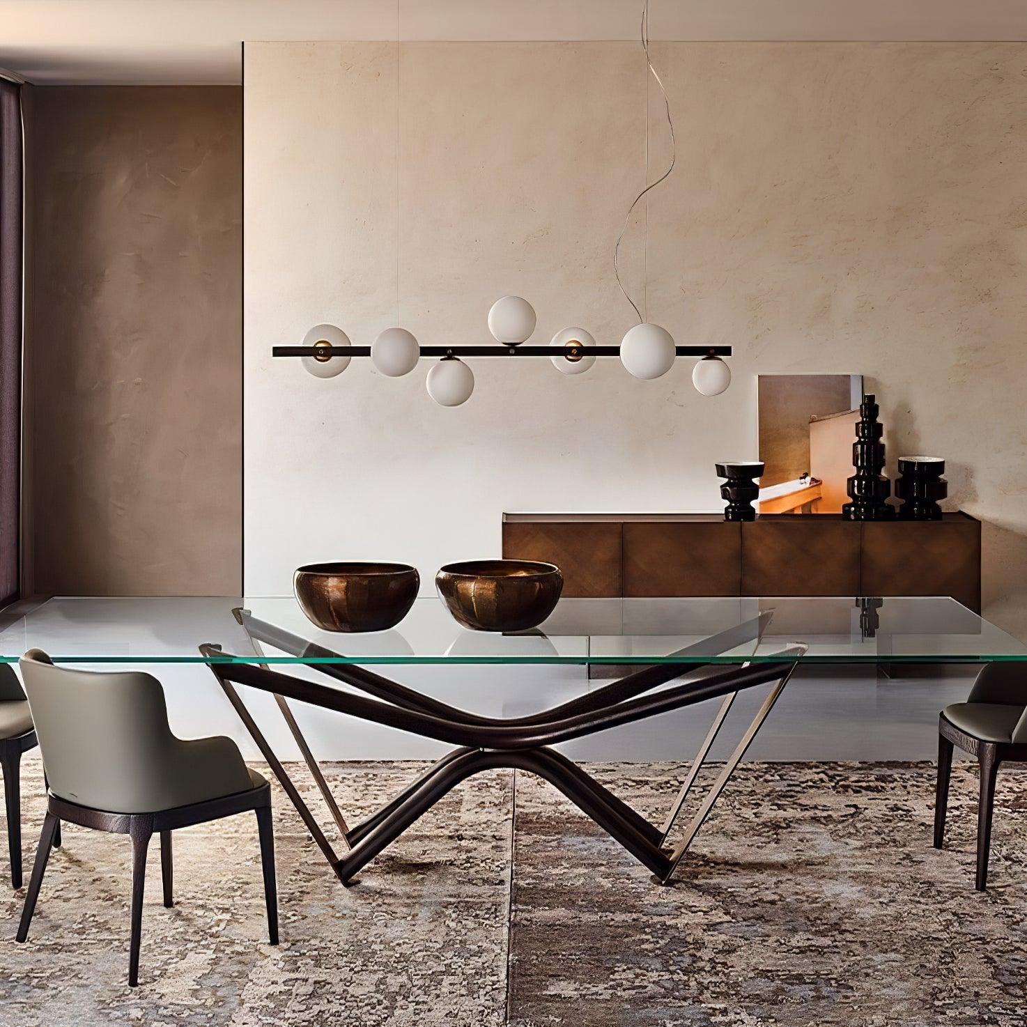 Globe pendant above glass table and two copper-tone bowls, with bronze-coloured sideboard, black stacked vessels and framed art.