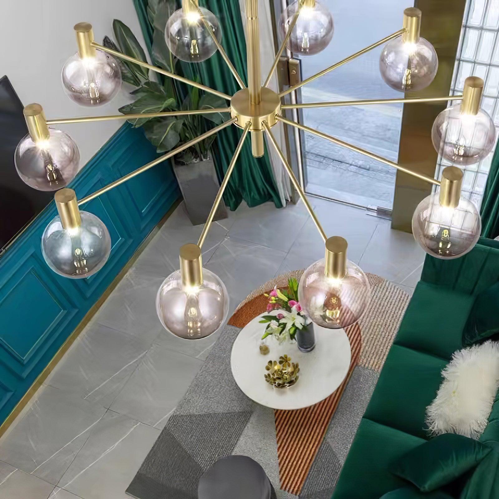 High angled view of clear globes on radial gold-tone arms above a green sofa and oval white table with flowers.