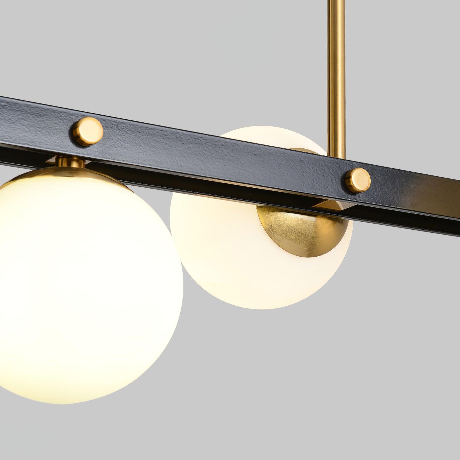 Close lit globe and brushed brass-tone cup beside textured black channel bar, round gold-tone fasteners and a vertical rod.
