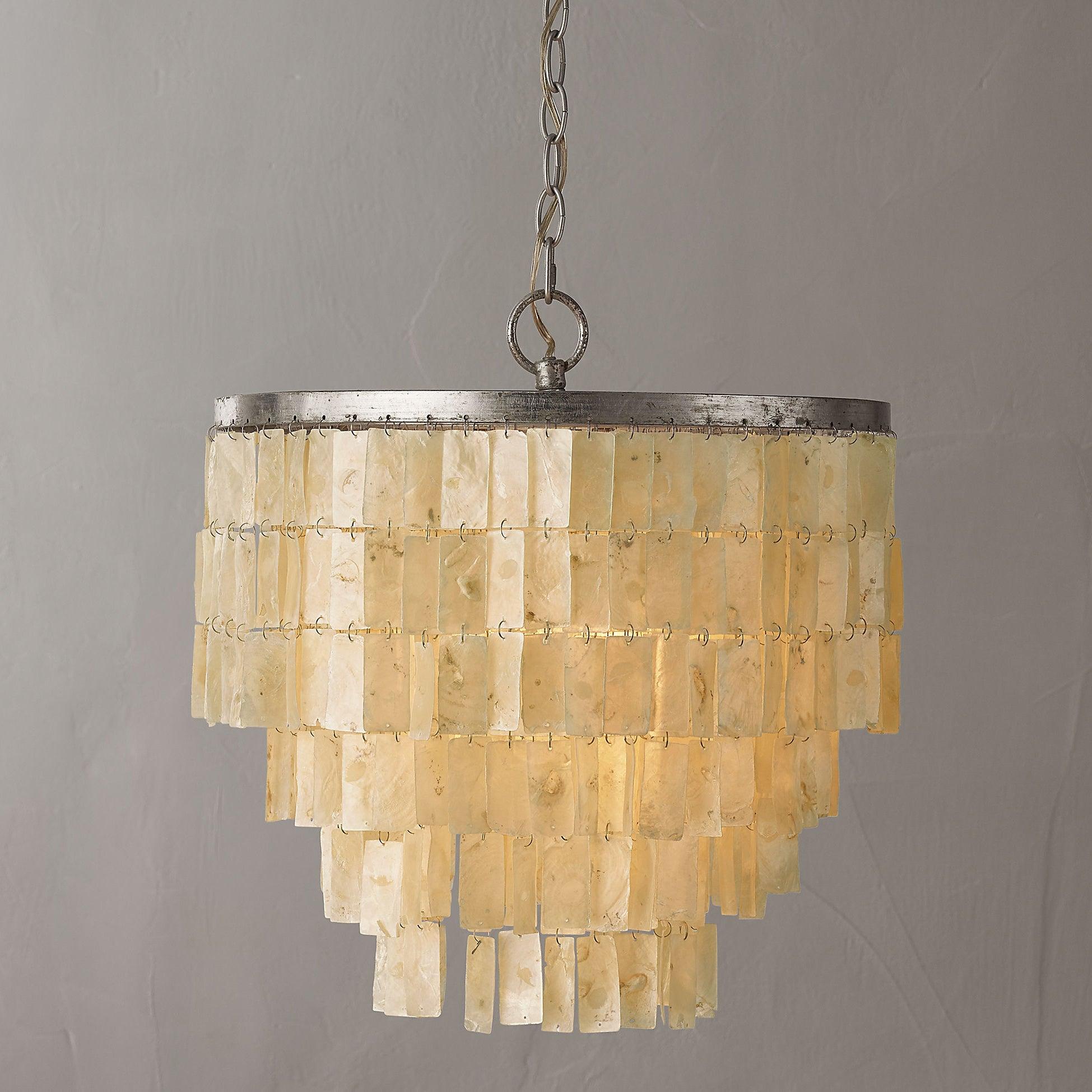 Frontal view of pale shell tiles with cream and brown markings, silver top ring and chain against a grey wall