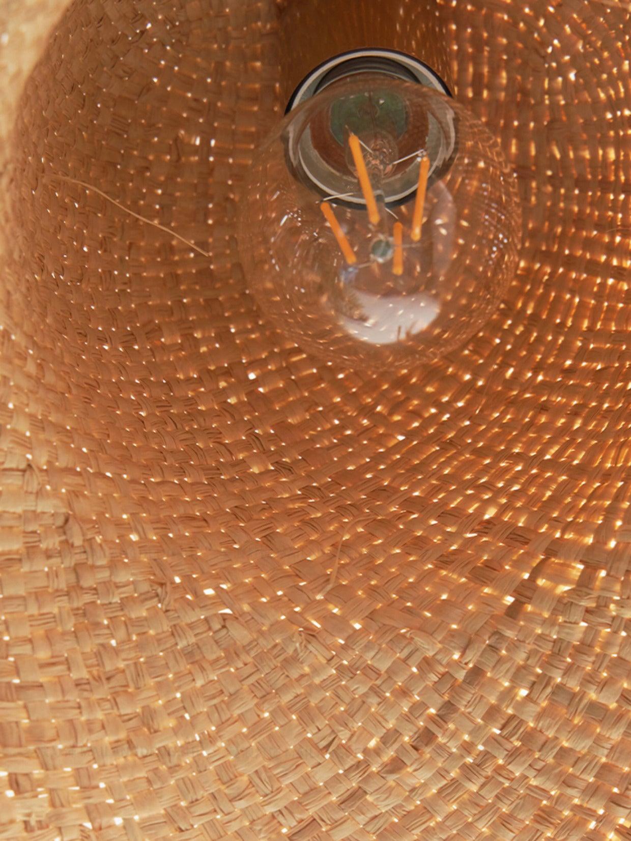 Interior close-up showing one clear filament-style bulb in a round holder beneath the woven hat crown