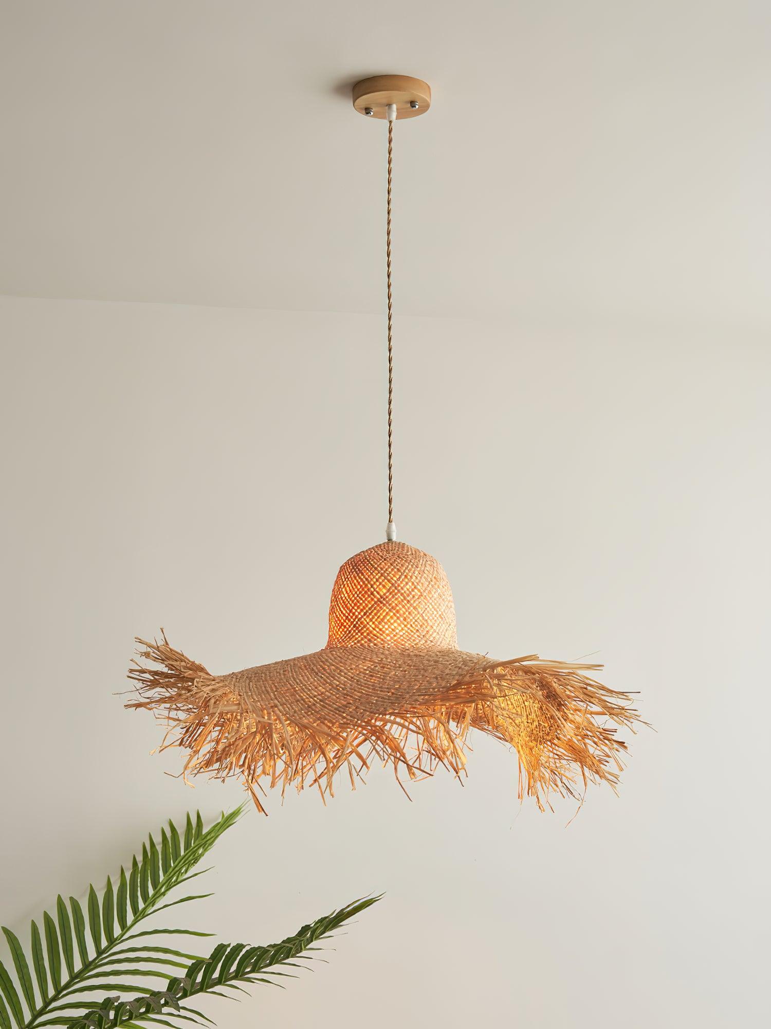 Alternate warm-lit full view of the fringed hat shade, twisted tan cord and round canopy beside a palm