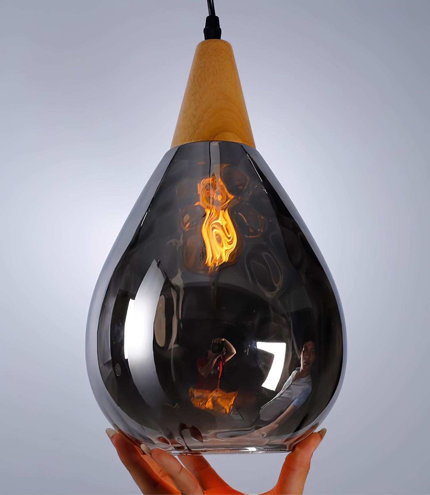 Smoky glass pendant held upright with the bulb illuminated