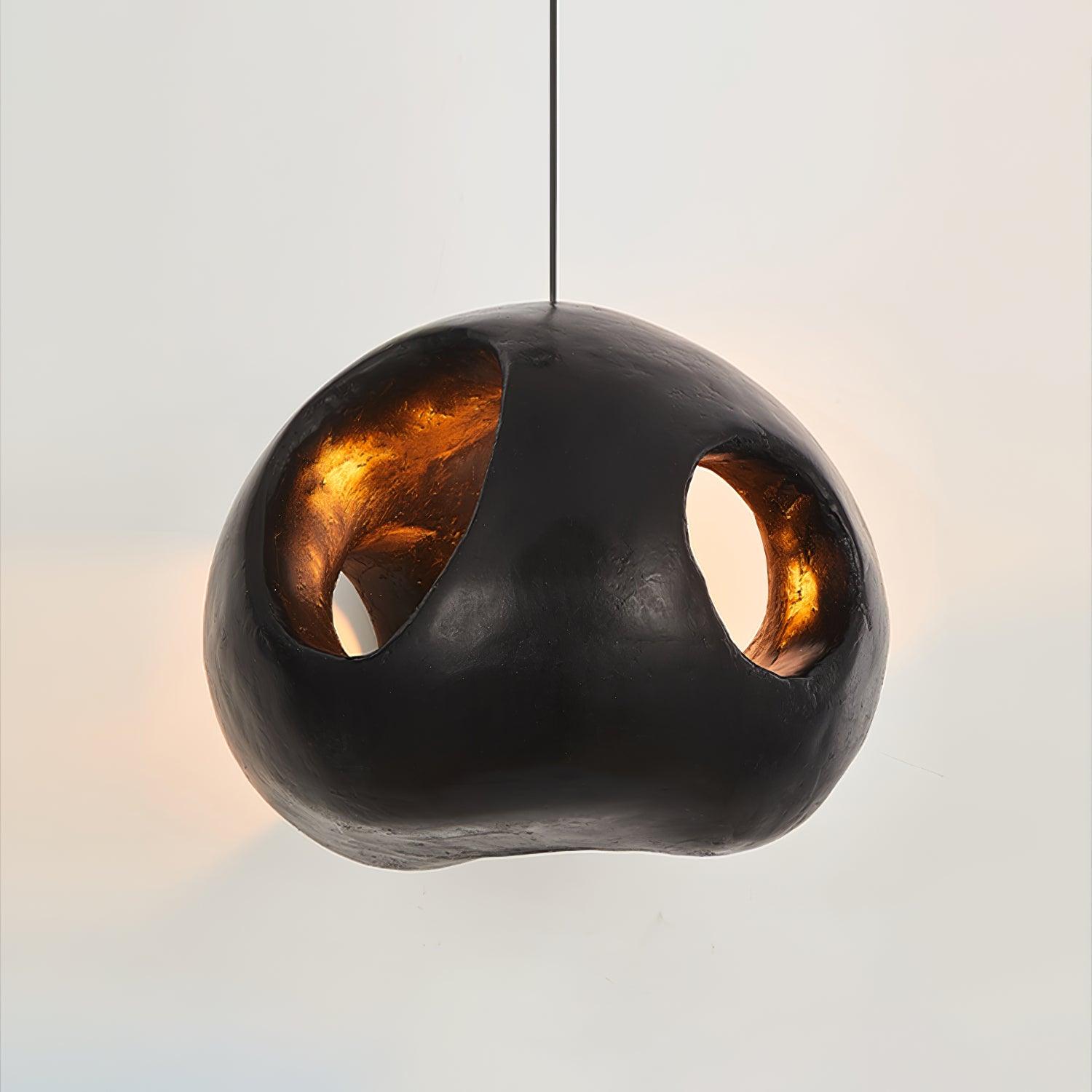 Close front view of the black rounded pendant and oval openings, with a warm-tone interior against a pale grey background