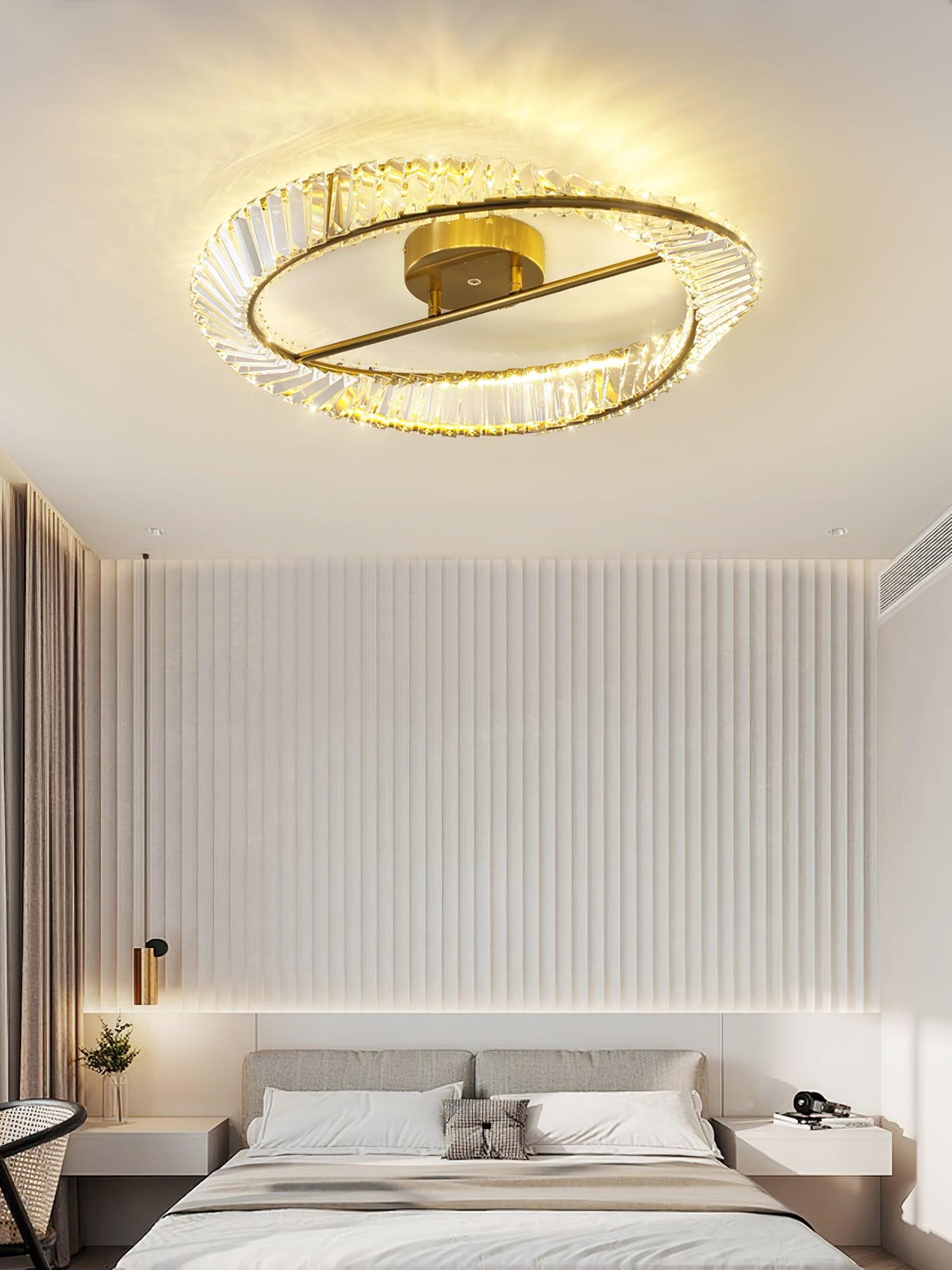 Illuminated ring ceiling light above a grey bed against a white vertical-panel wall
