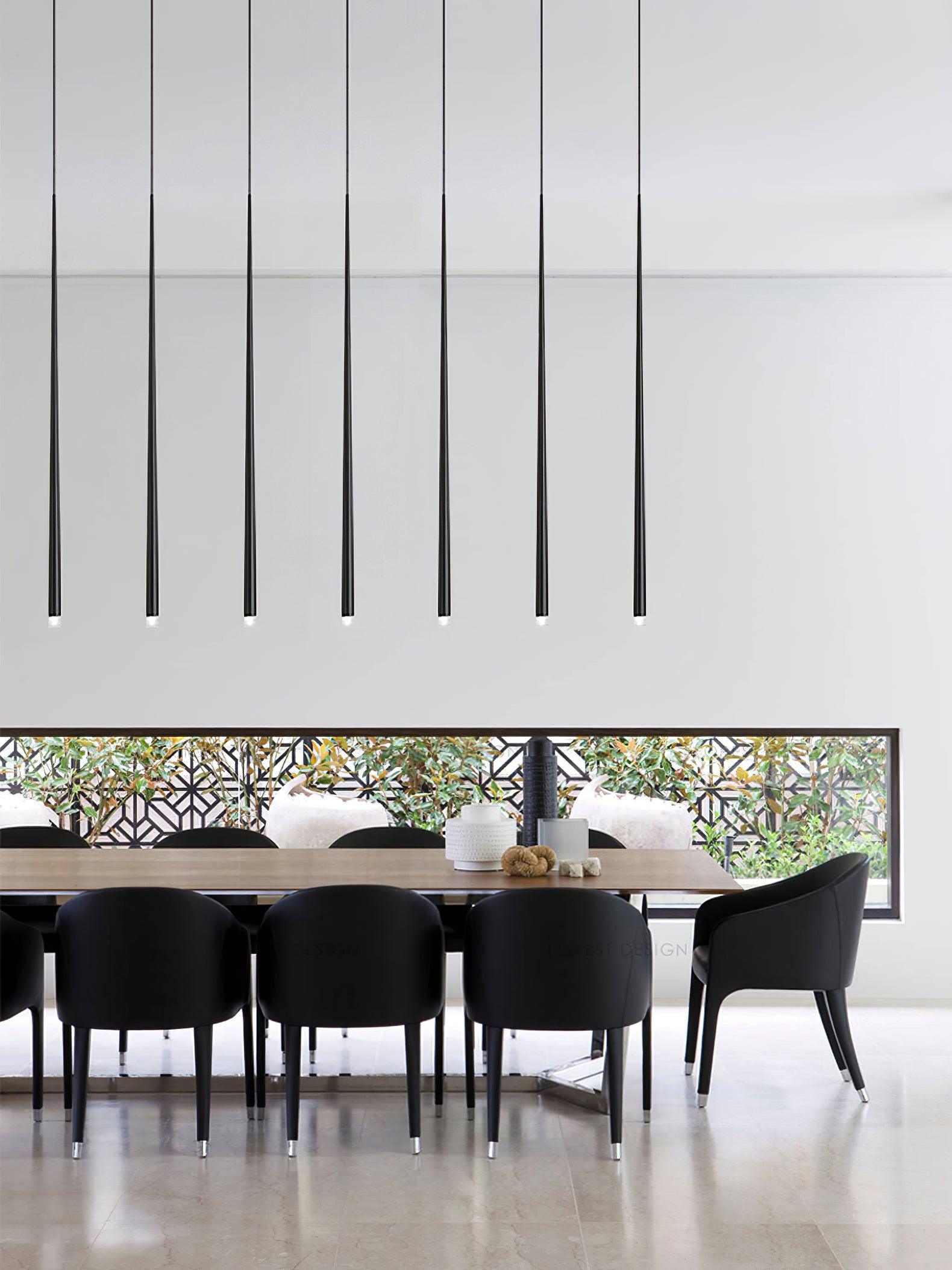 Seven narrow black tube pendants above a wooden dining table with black chairs