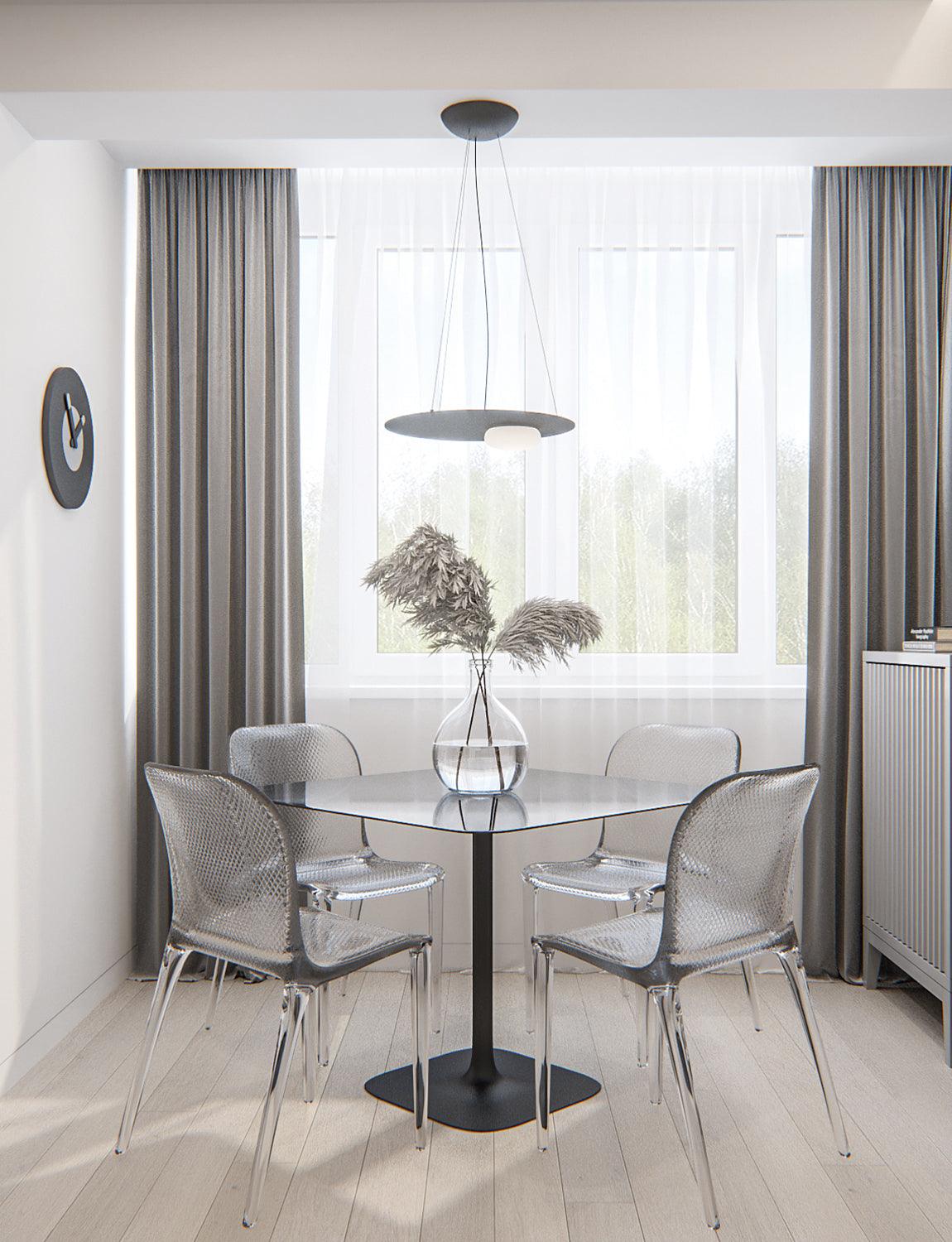 Black pendant and round canopy above black table, four transparent chairs and vase, by bright window, grey curtains and wall clock.