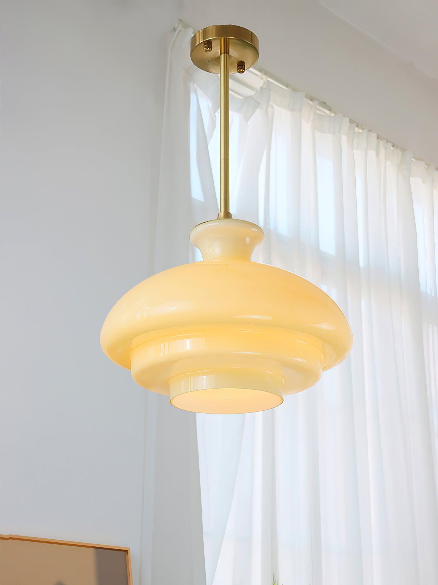 Lit yellow dome with gold-tone canopy and rod beside white window curtains and partial framed artwork