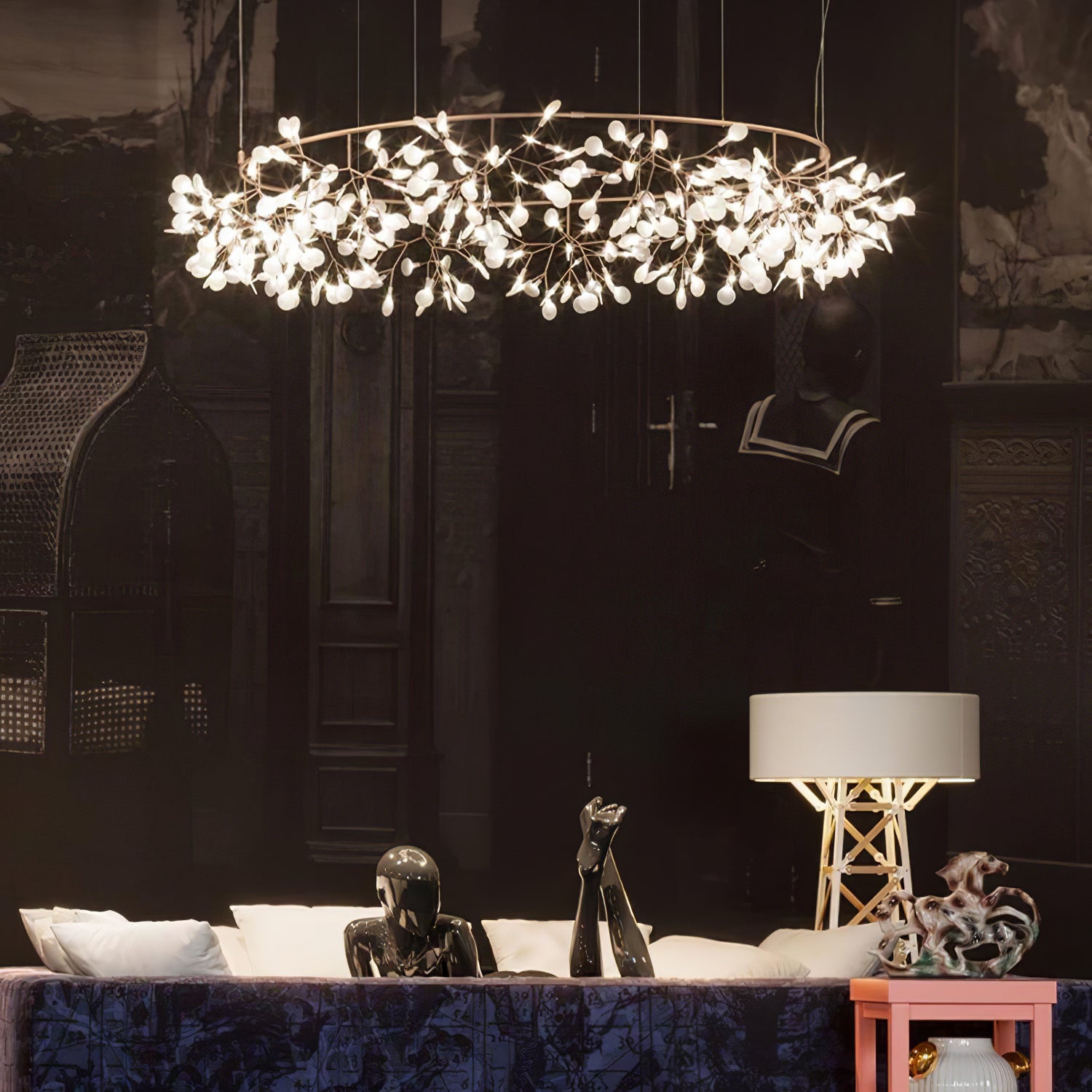 Pale metallic leaf ring chandelier in an eclectic lounge with sculptural busts and a patterned sofa